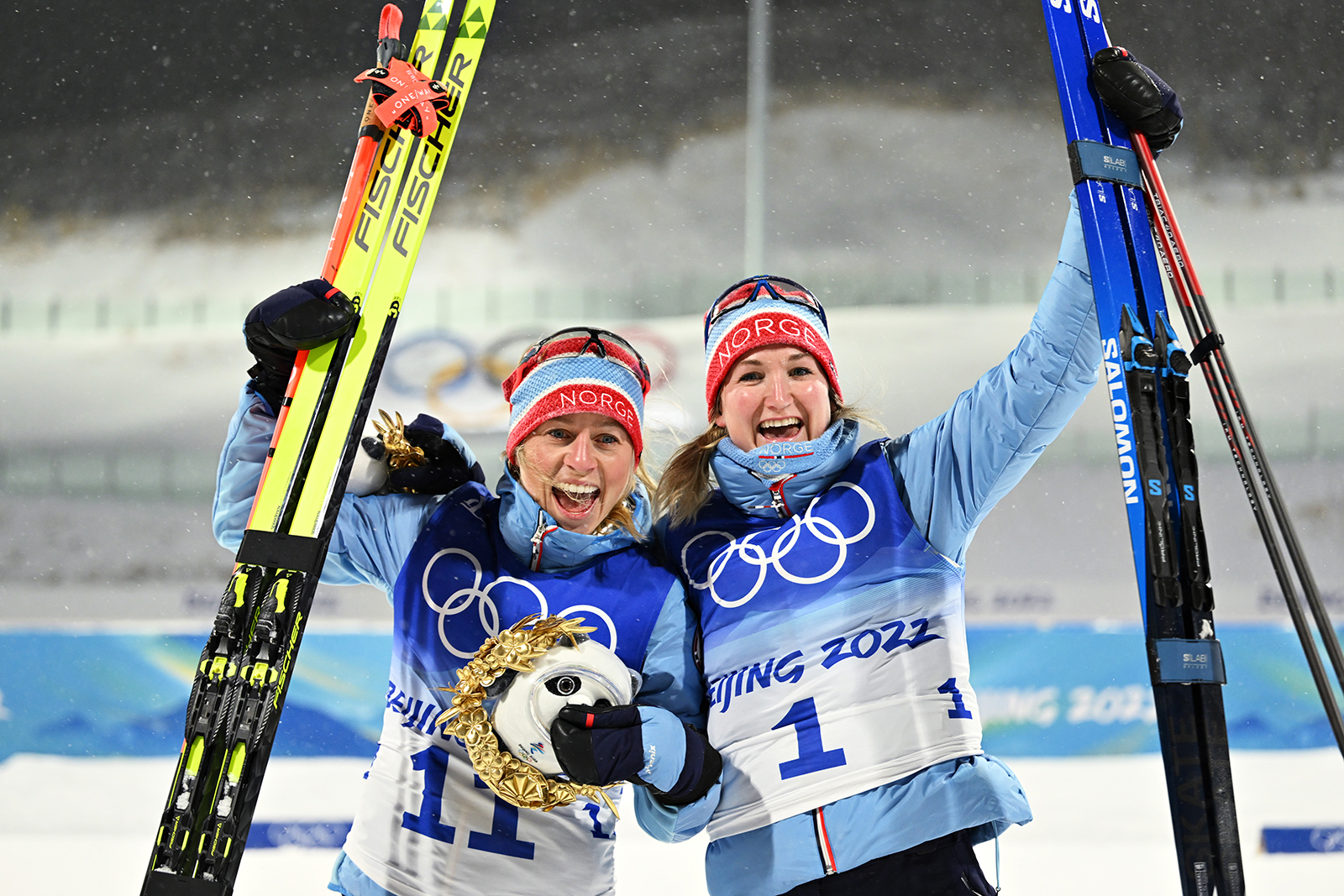 Bronze medalist Tiril Eckhoff, left, and gold medalist Marte Olsbu Roeiseland of Team Norway celebrate at the biathlon women's 10km pursuit flower ceremony on Sunday.