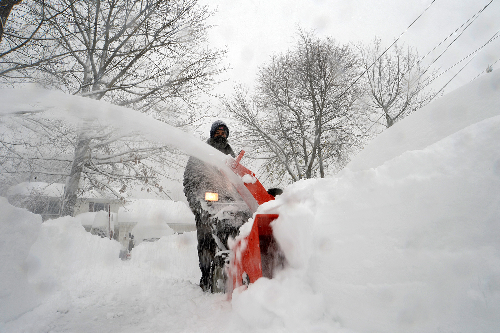 Joe Ahmed uses a snowblower to dig out after an intense lake-effect snowstorm impacted the area in Hamburg, New York, on on Friday, November 18.