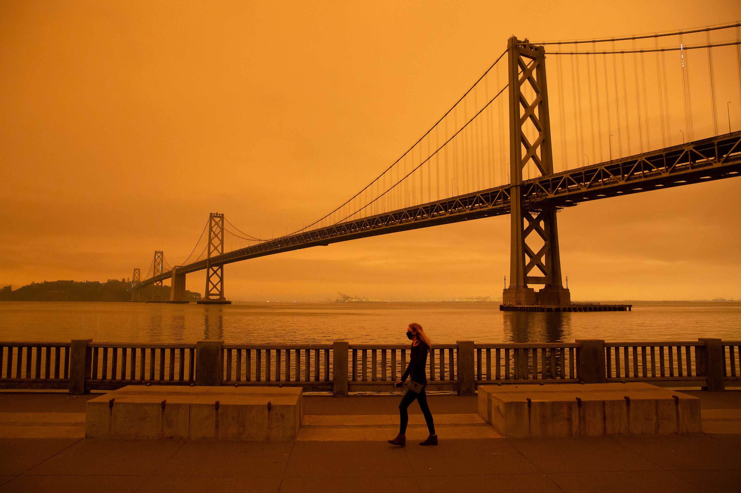 A woman walks along The Embarcadero under an orange smoke-filled sky in San Francisco, California on September 9.