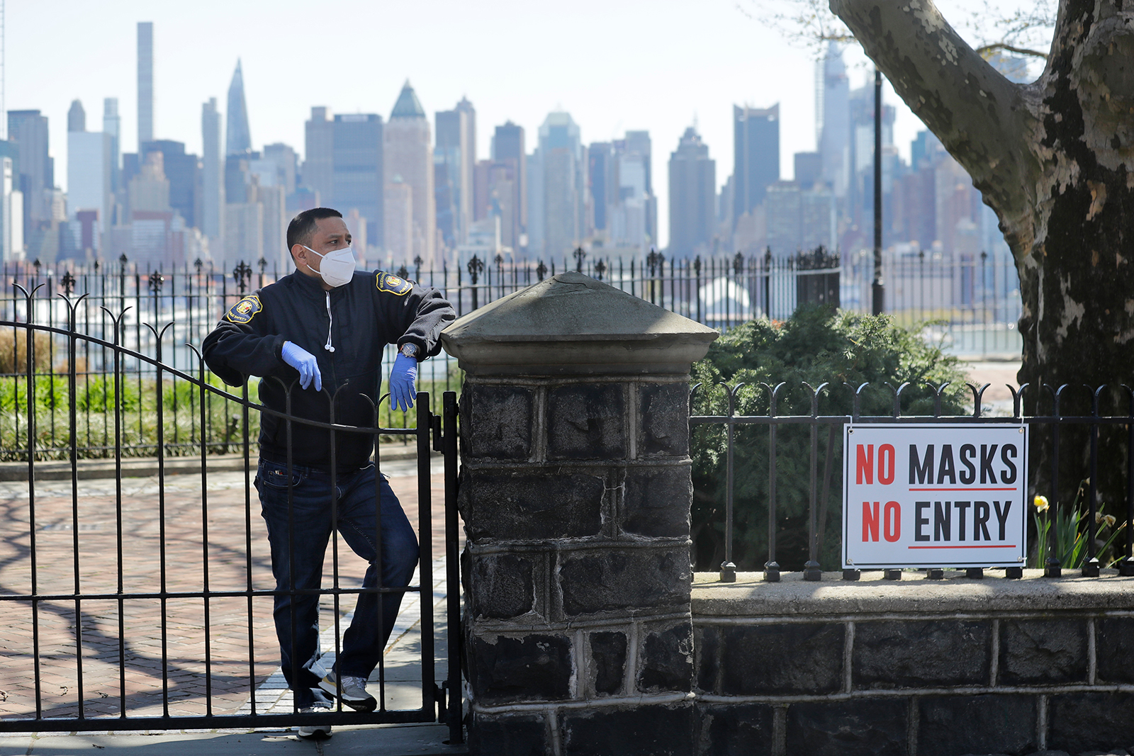 A public safety officer stands behind the gates of temporarily closed park at a crowded viewing point for a flyover by the Navy’s Blue Angels and the Air Force’s Thunderbirds of the New York City skyline in Weehawken, New Jersey, on April 28.