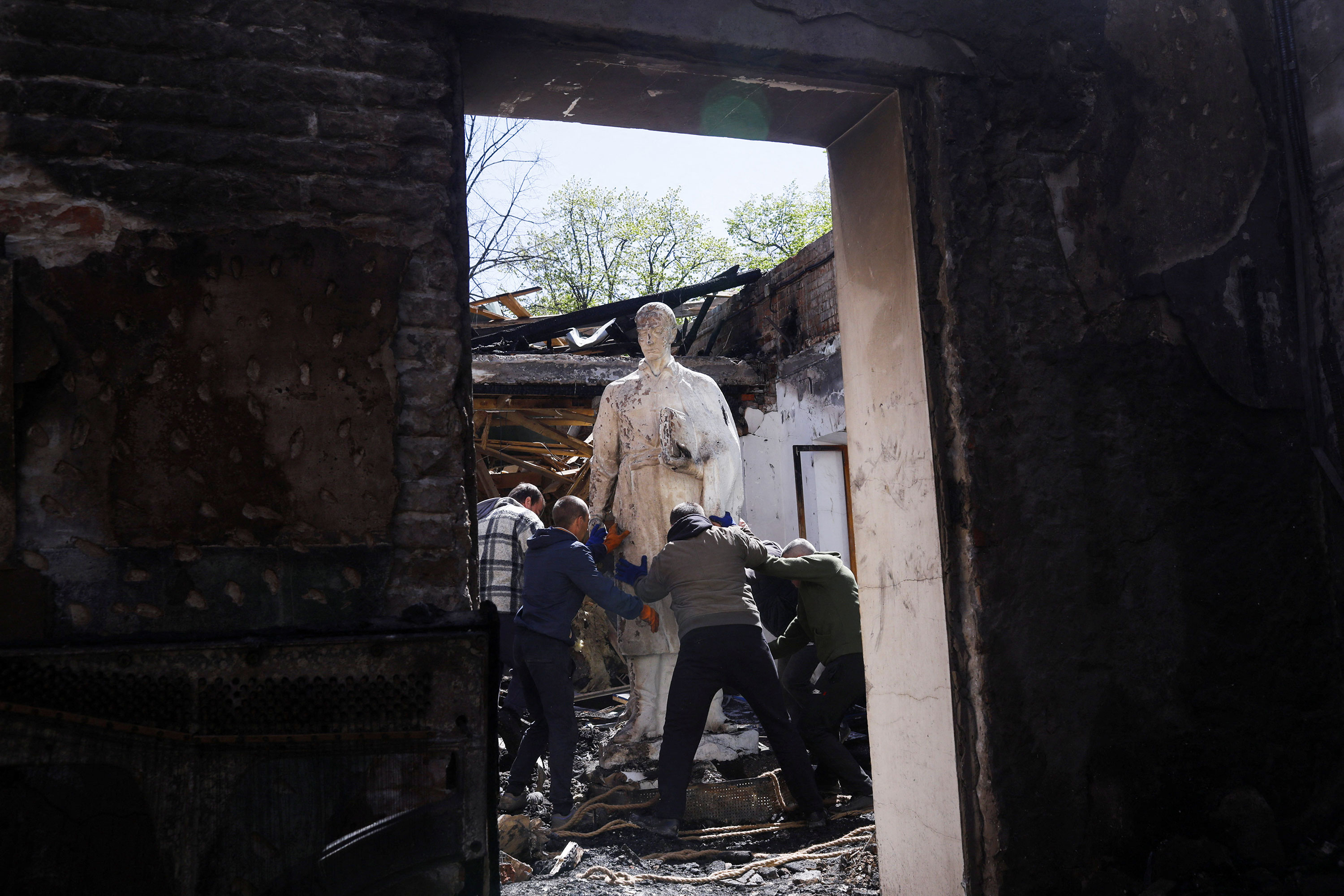 People remove the statue of Ukrainian philosopher Hryhoriy Skovoroda from the destroyed Hryhoriy Skovoroda Literary Memorial Museum in Skovorodynivka, Ukraine, on May 7.