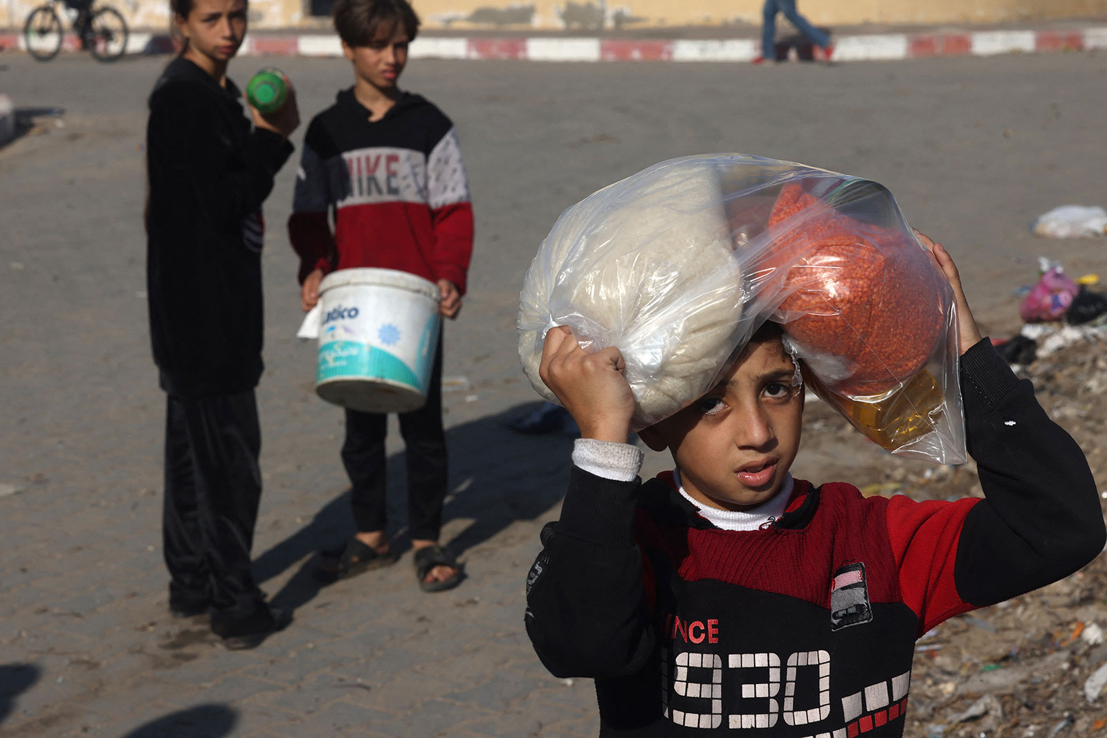 Palestinian children collect food at a donation point provided by a charity group in Rafah, on Tuesday, December 6.