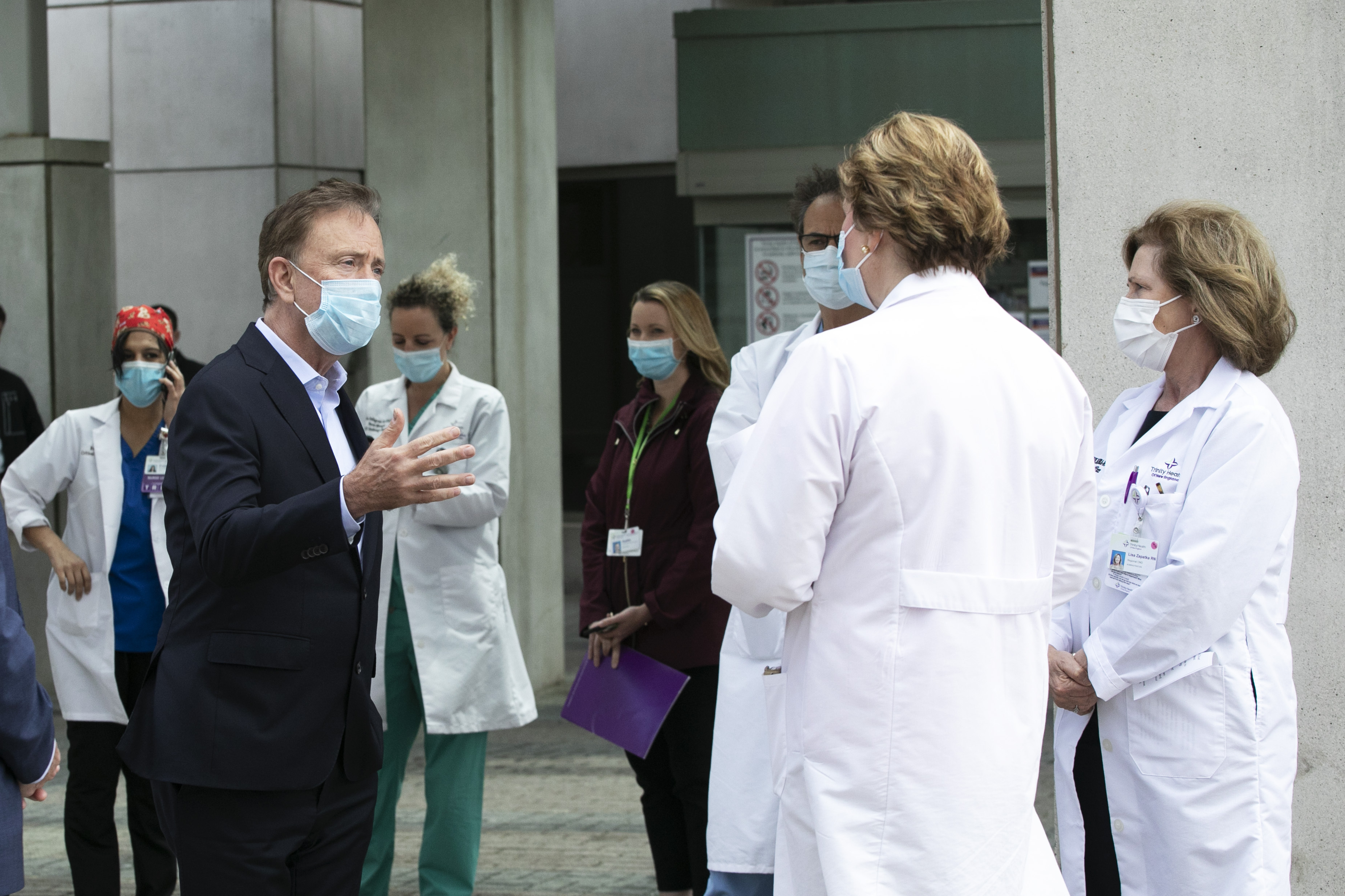 Gov. Ned Lamont, left, talks with medical staff outside Saint Francis Hospital, on May 7, in Hartford, Connecticut.