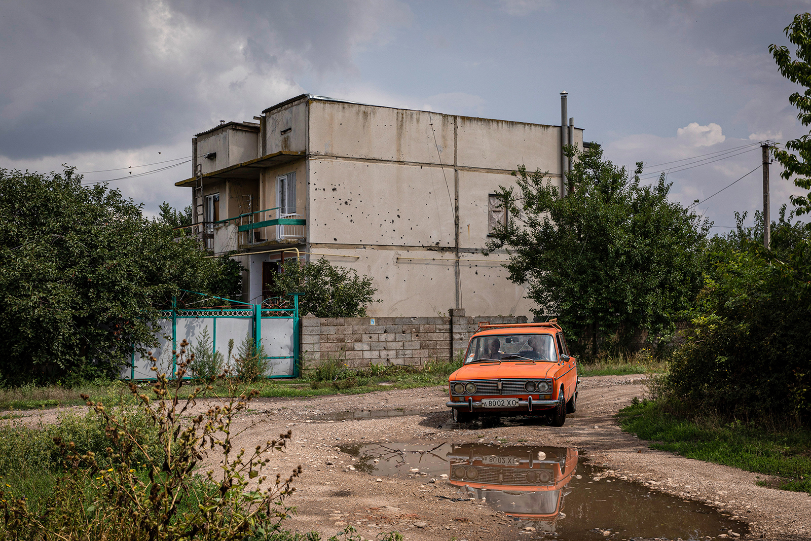 A car is driving past a building damaged by Russian shelling in the village of Shevchenkove in August.