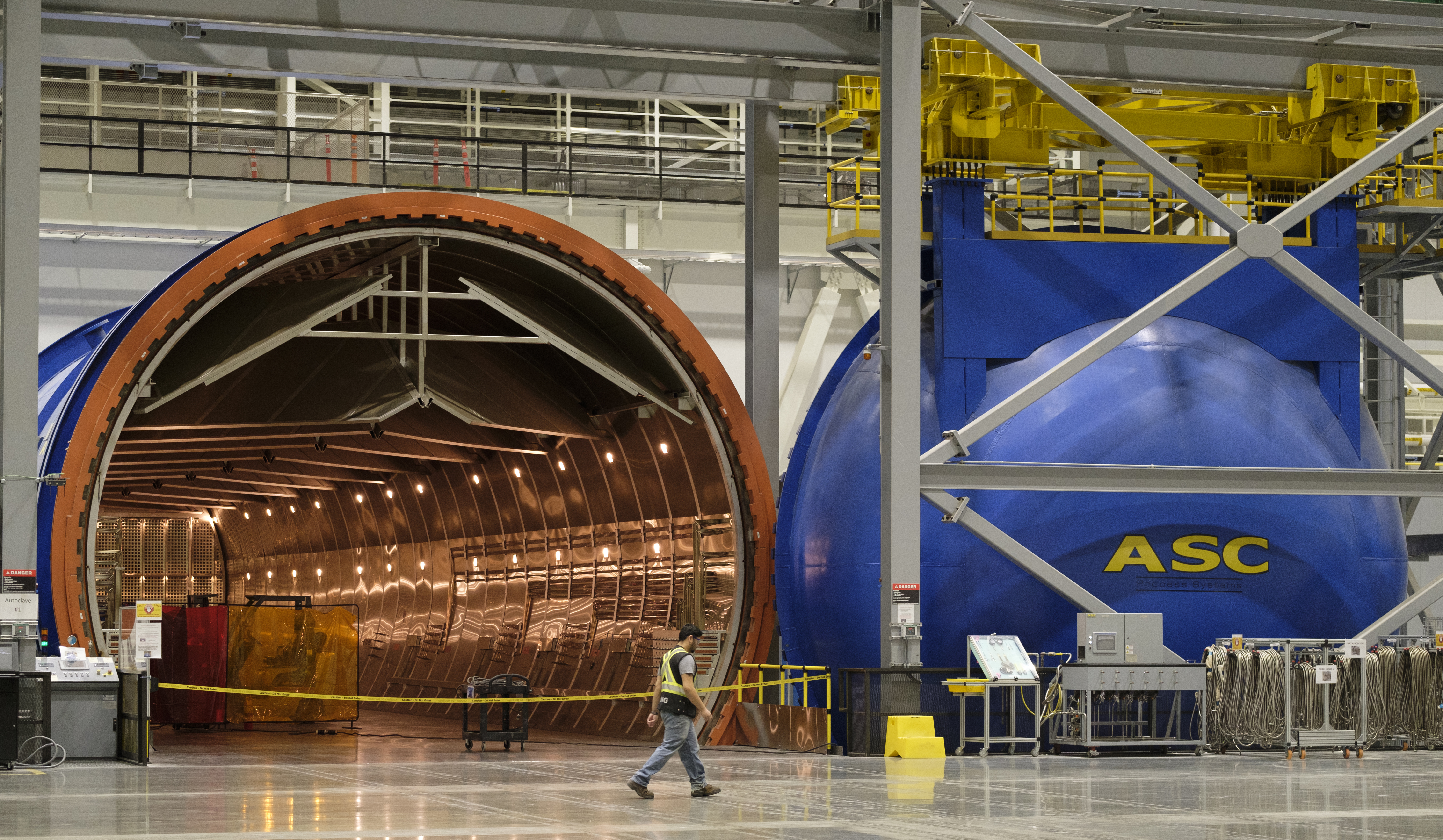 A worker walks past a giant autoclave, which provides superheated pressure needed in the construction of the new 777X composite wing at the Boeing 777X Composite Wing Center in Everett, Washington. 