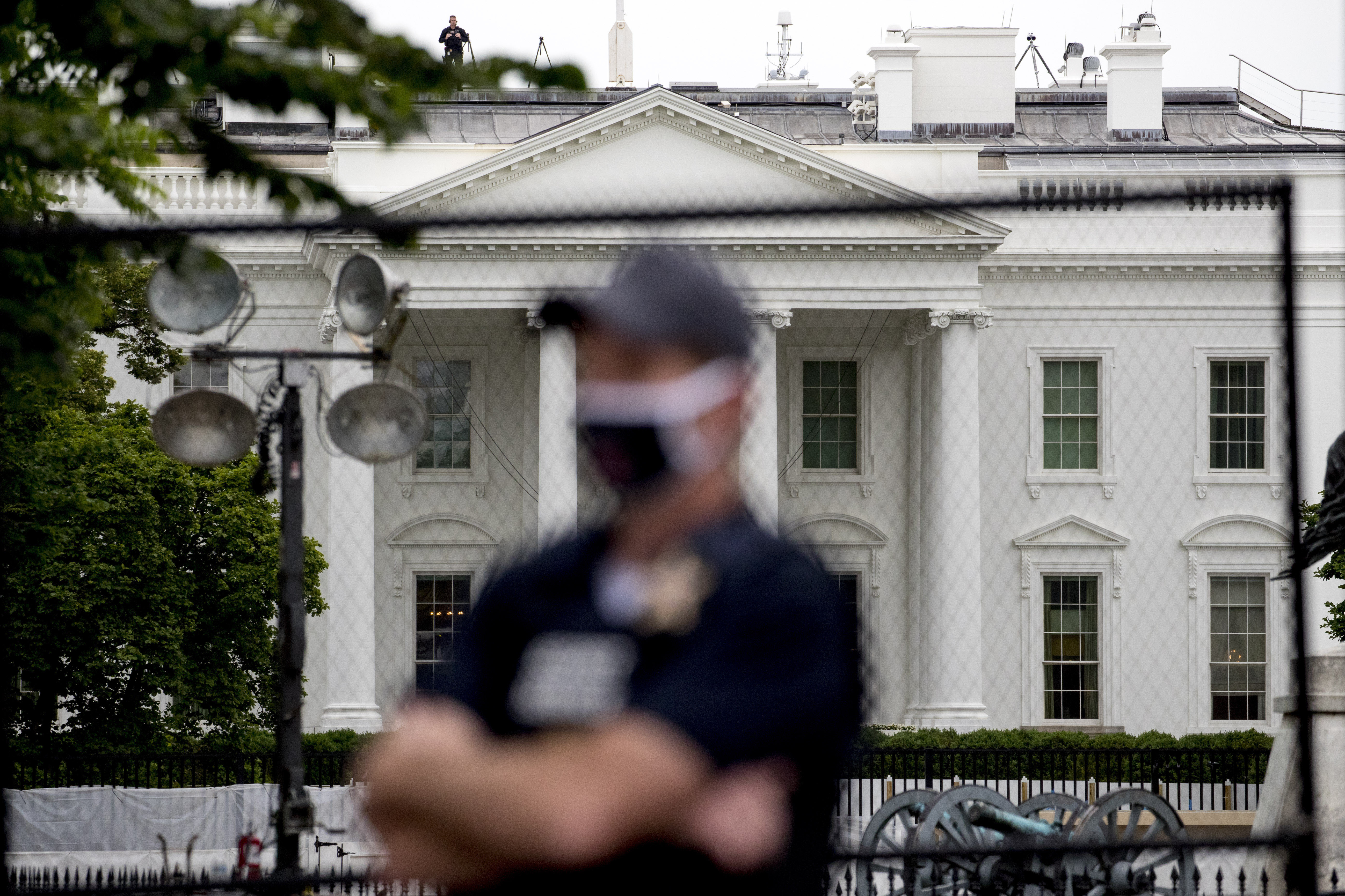 The White House is visible behind a large security fence as a Secret Service agent stands in front of Lafayette Park in Washington on June 2.