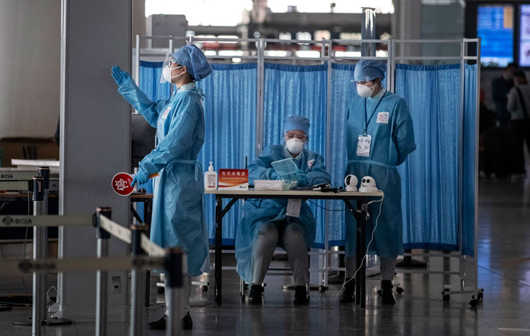 Chinese airport security wear protective suits as they wait to check temperatures and health of travelers at Beijing Capital International Airport on March 24, in Beijing, China.