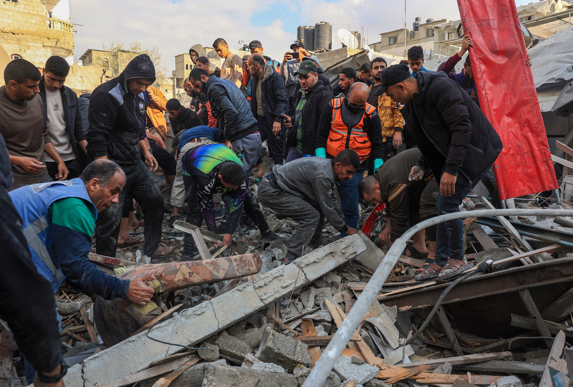 Rescuers and civilians look for survivors amid the rubble of destroyed buildings following Israeli bombardment in Rafah, southern Gaza, on December 14, 2023.