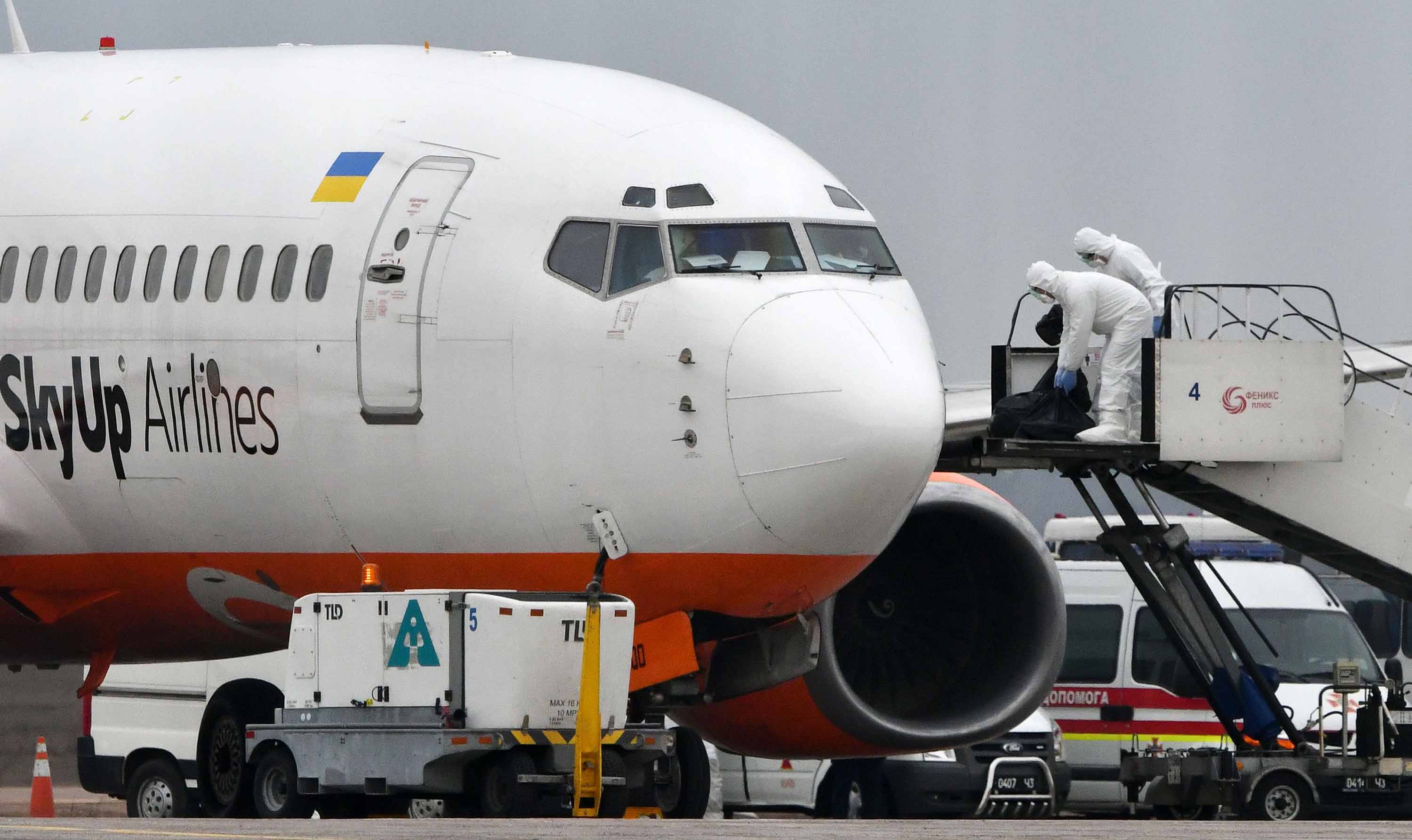 Airport crew members check the fuselage of a SkyUp Airlines plane during a refueling stopover at Kiev's Boryspil International Airport in Ukraine, following the evacuation of Ukrainians and foreign nationals from the Chinese city of Wuhan on Thursday.