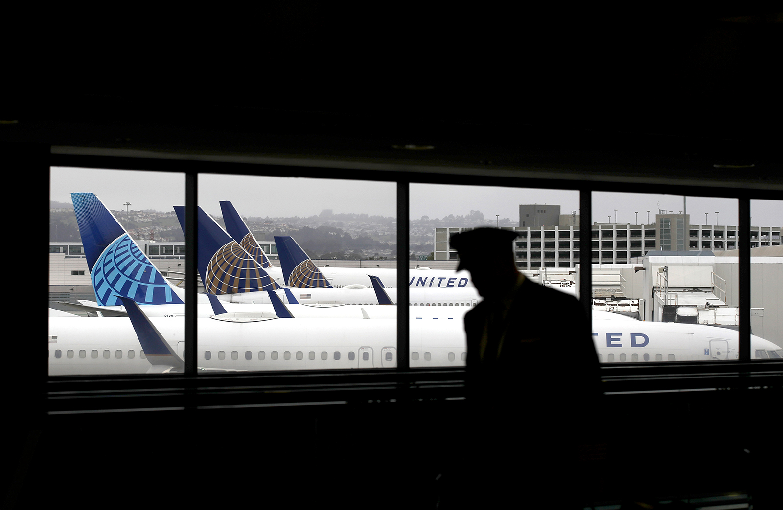 A pilot walks by United Airlines planes as they sit parked at gates at San Francisco International Airport, on April 12.