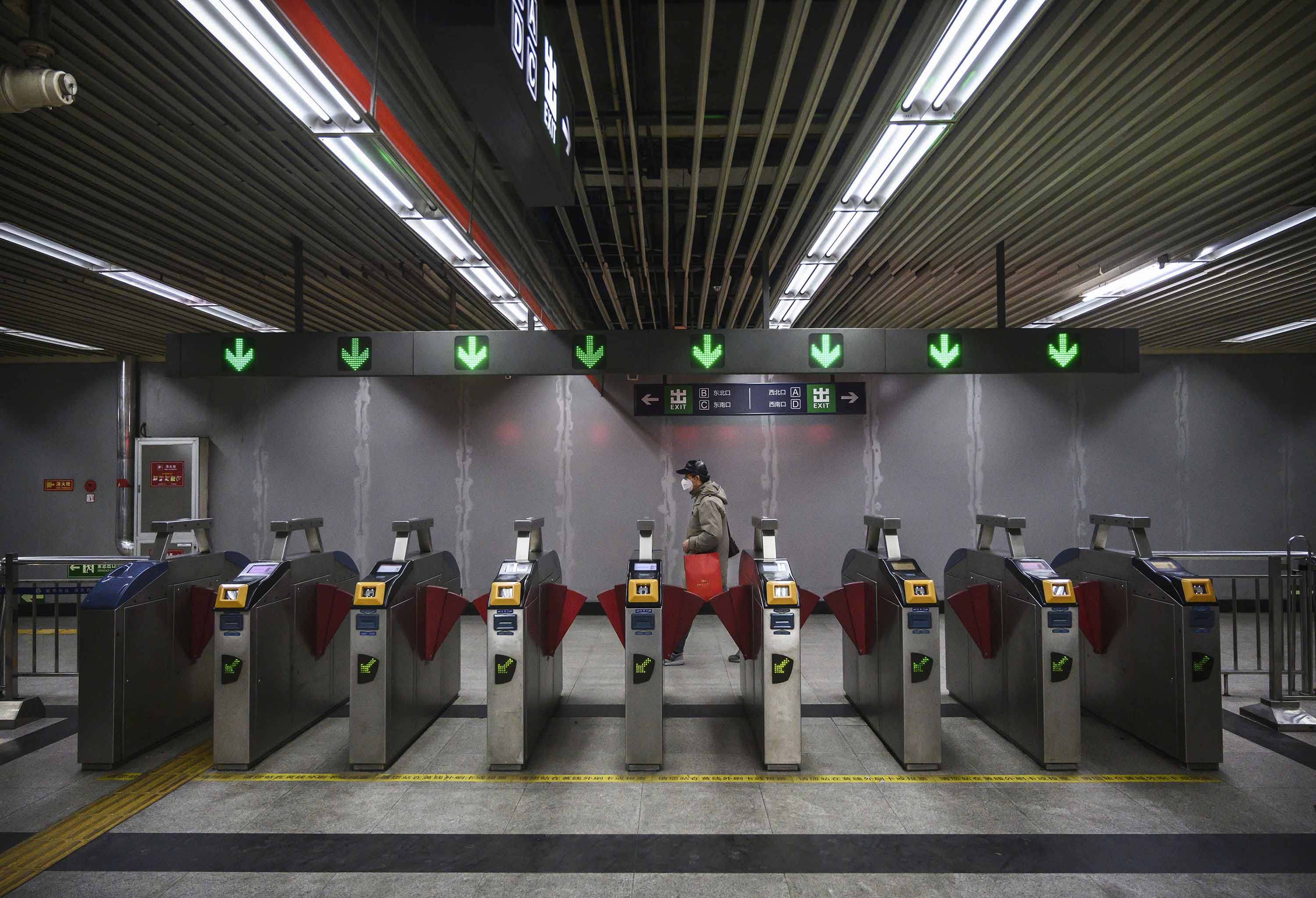A Chinese man wears a protective mask as he walks by an exit area in a subway station in Beijing, on February 14.