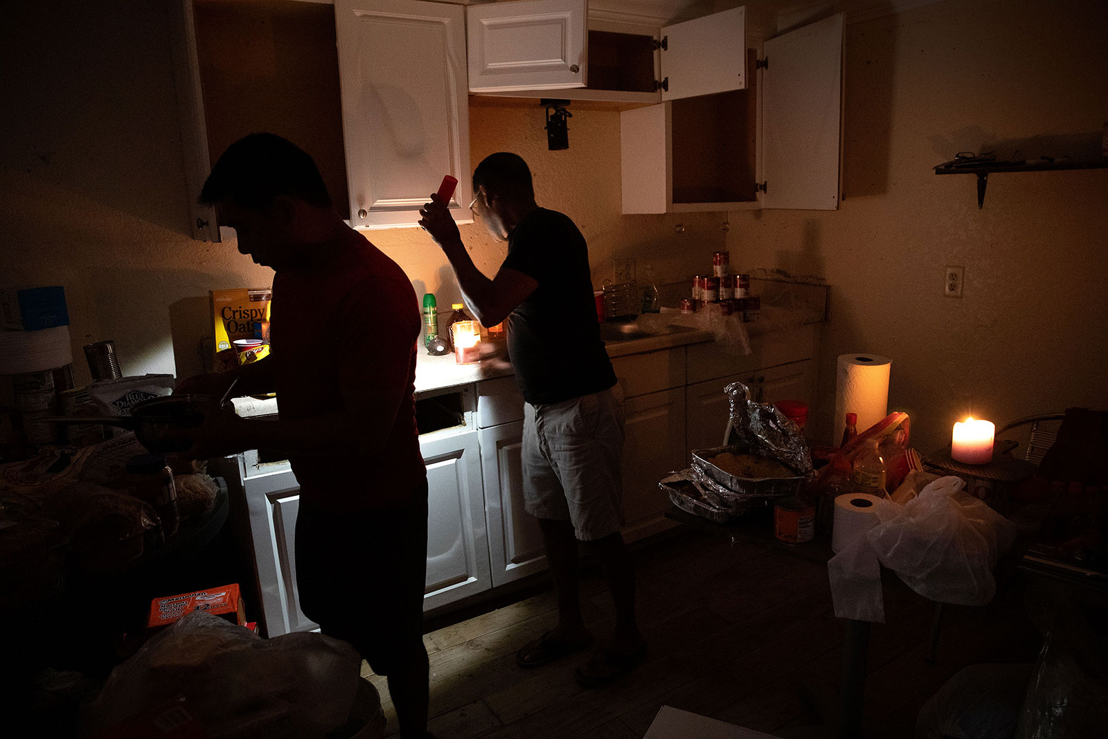 Jose Ramirez, a resident of the San Carlos Island mobile home park, washes dishes using a flashlight in his home in Fort Myers Beach.