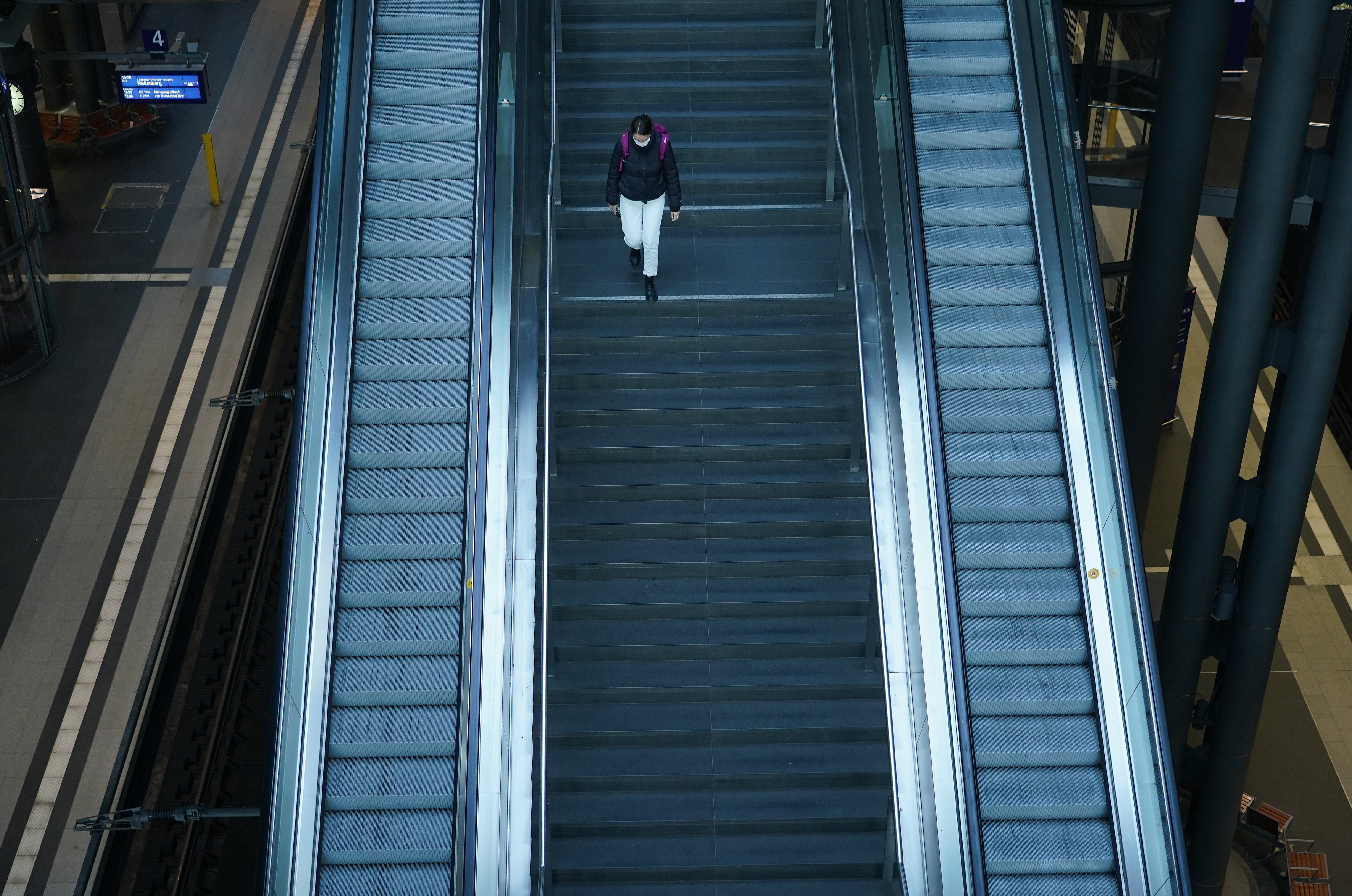 A woman wearing a protective mask walks stairs down to train platforms at nearly-deserted Hauptbahnhof main railway station on March 27 in Berlin, Germany. Public life has been restricted in an effort by authorities to slow the spread of infections. 