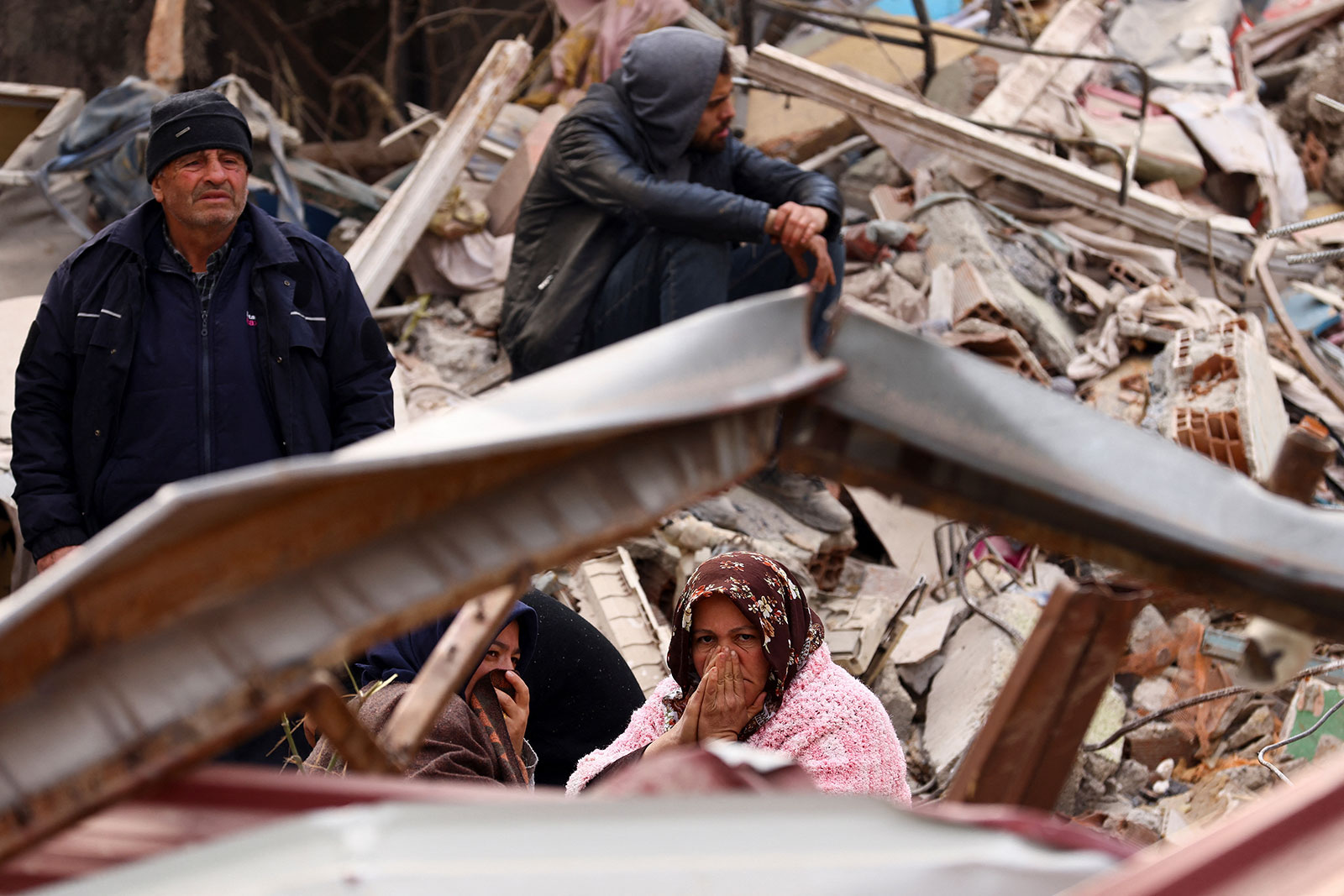 People sit and stand amid rubble in the aftermath of the earthquake in Kahramanmaras, Turkey, on Friday. 