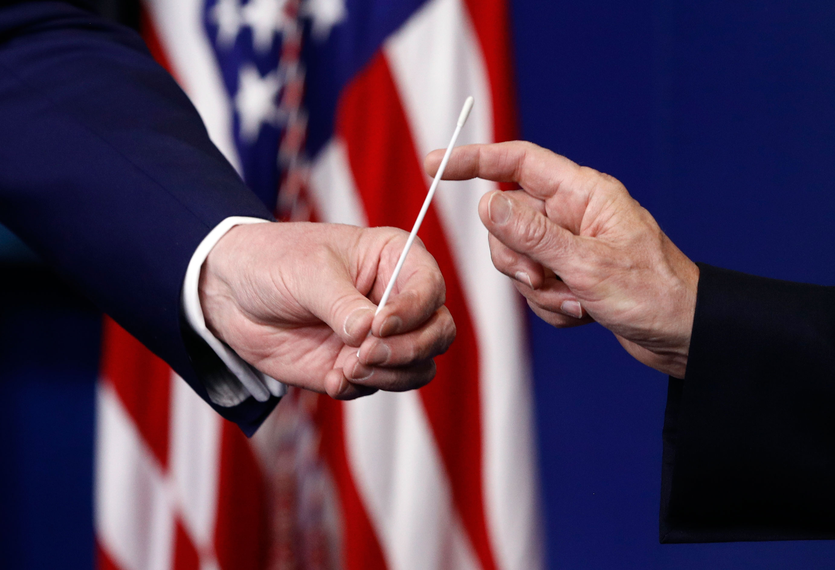 US President Donald Trump, left, hands a sample coronavirus testing swap to US Vice President Mike Pence during a coronavirus task force briefing at the White House, on April 19, in Washington. 