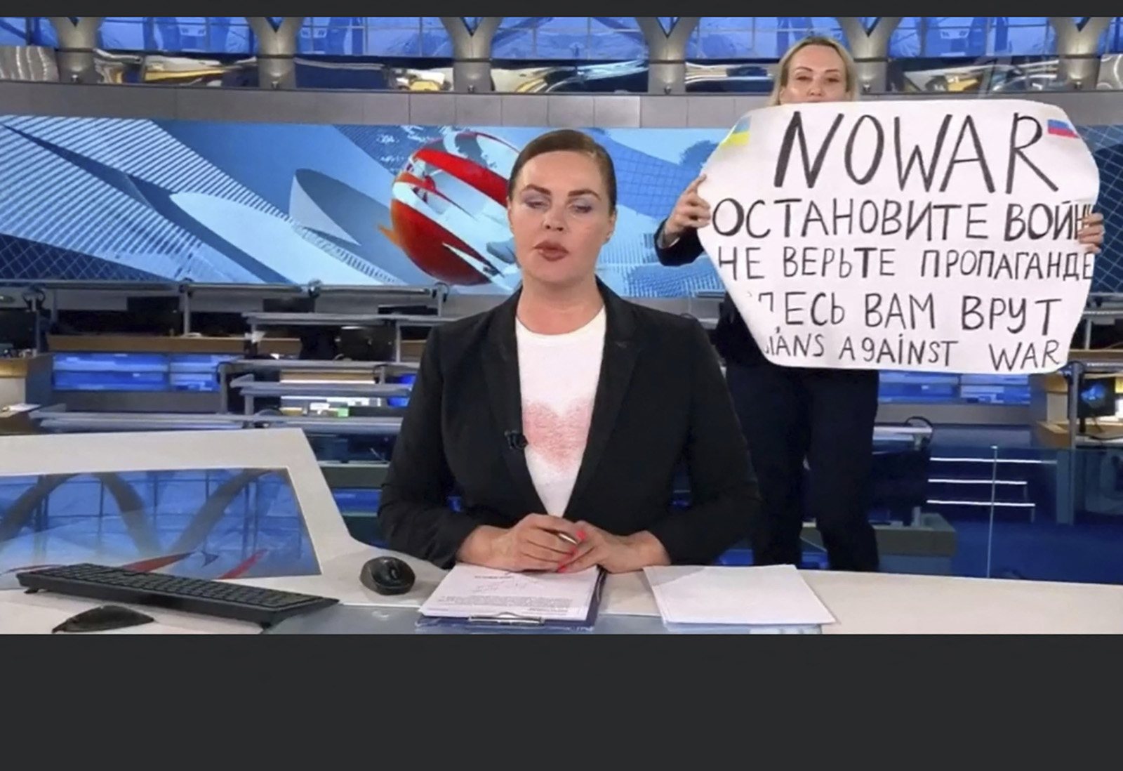 This video grab shows Russian Channel One editor Marina Ovsyannikova holding a poster reading "Stop the war. Don't believe the propaganda. Here they are lying to you" during a live broadcast by Yekaterina Andreyeva in Moscow, Russia, on March 14