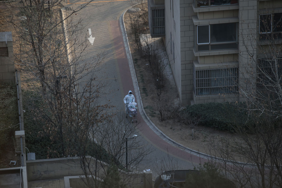 A staff member in a protective suit transports supplies in a cart in Daxing district of Beijing, China on January 20.