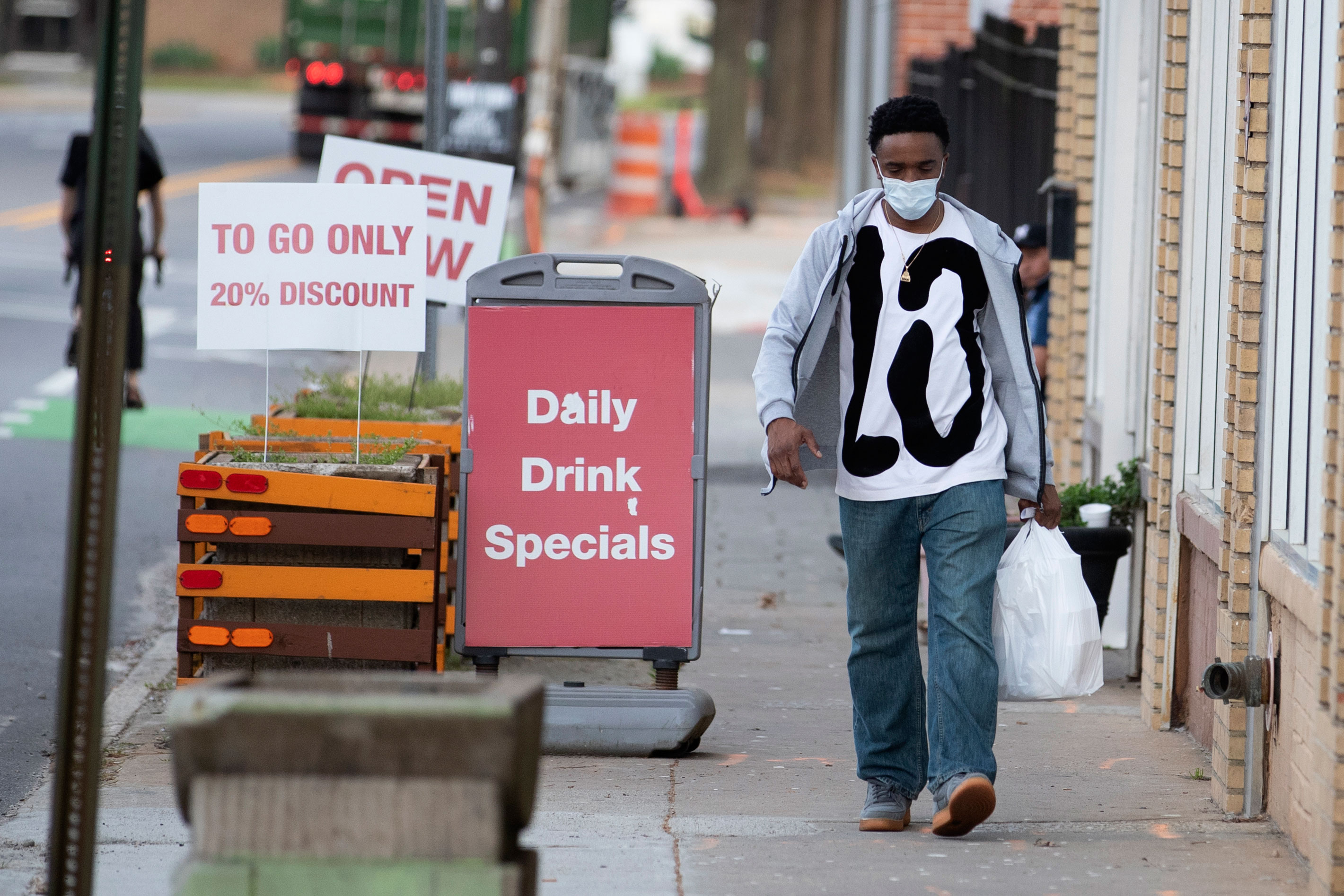 A man leaves a restaurant with a take-out order on March 19 in Atlanta.