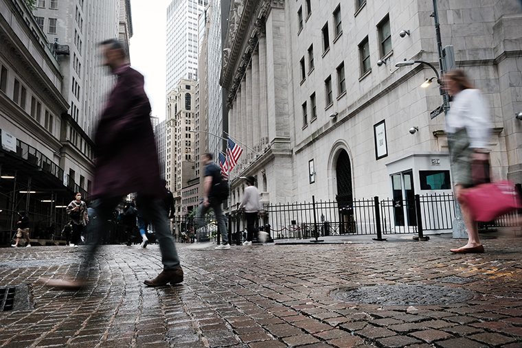 People walk by the New York Stock Exchange on June 16.