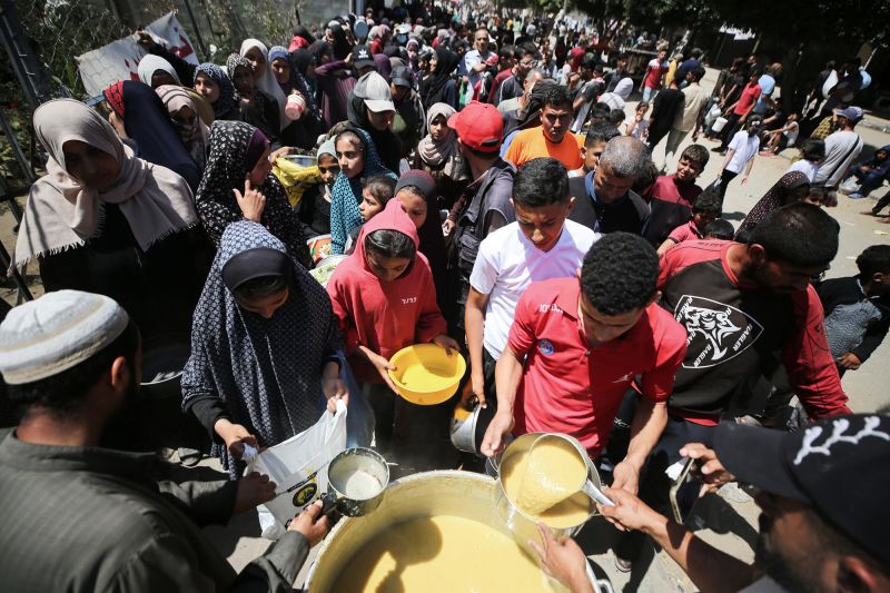 Vertriebene Palästinenser erhalten am 19. April an einer Spendenstelle in Deir al-Balah, Gaza, gekochte Essensrationen.
