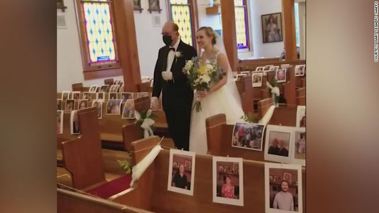 Clare Keefer is walked down the aisle by her father in the church decorated with pictures of the guests, who were unable to attend because of the coronavirus pandemic.