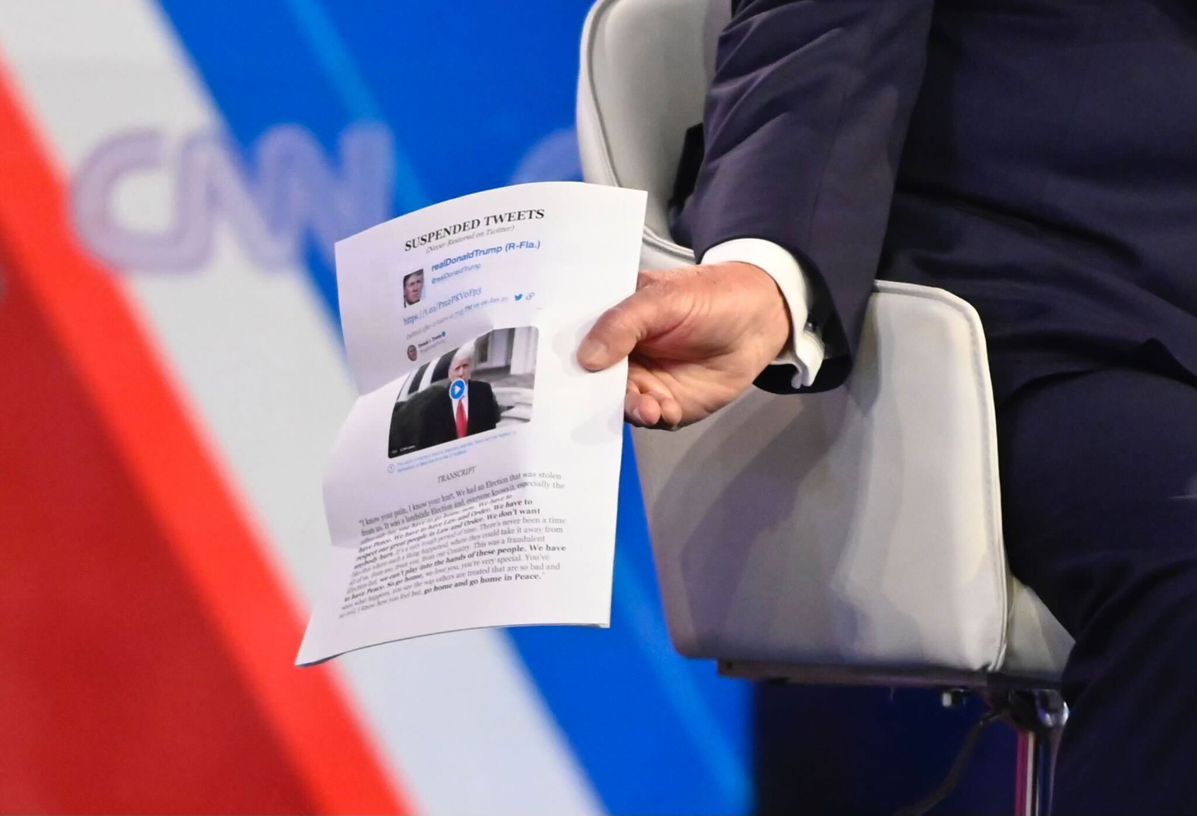 Trump holds notes of his tweets. The top of the page says, "SUSPENDED TWEETS (Now Restored on Twitter)."