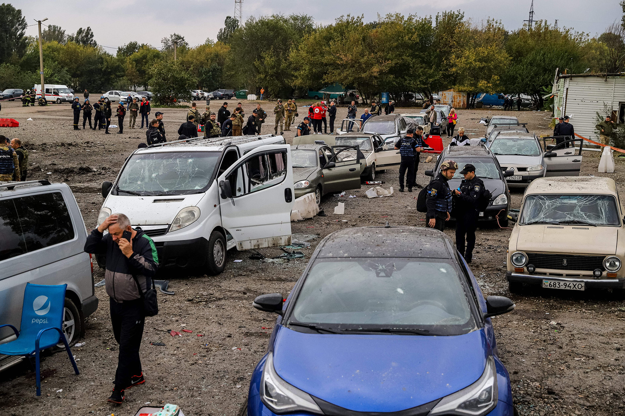 People walk between cars damaged by a missile strike on a road near Zaporizhzhia, Ukraine, on September 30.