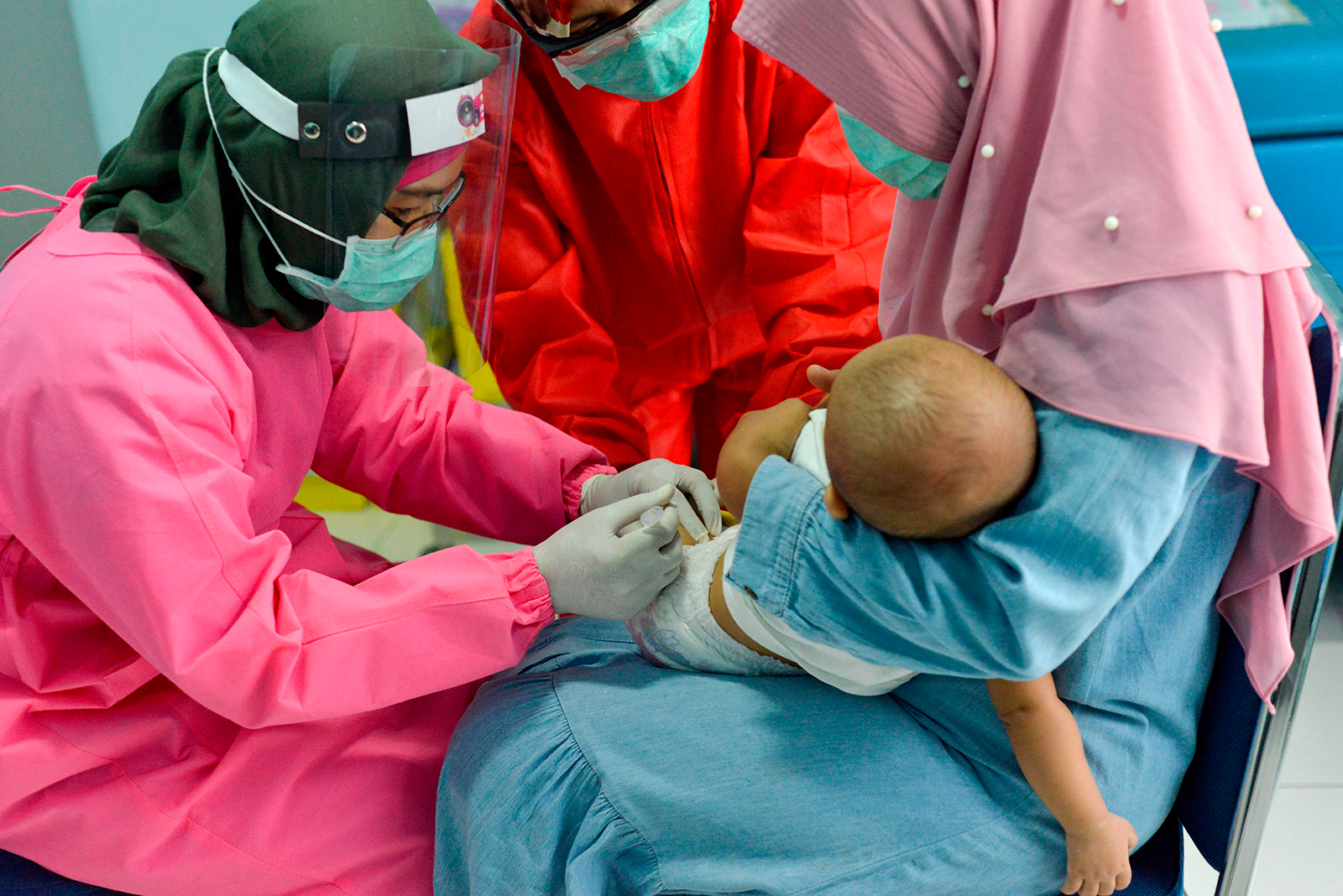 Indonesian medical staff wearing protective gear administer vaccines for rubella and polio on a baby at a community health centre in Banda Aceh on Monday, May 18.