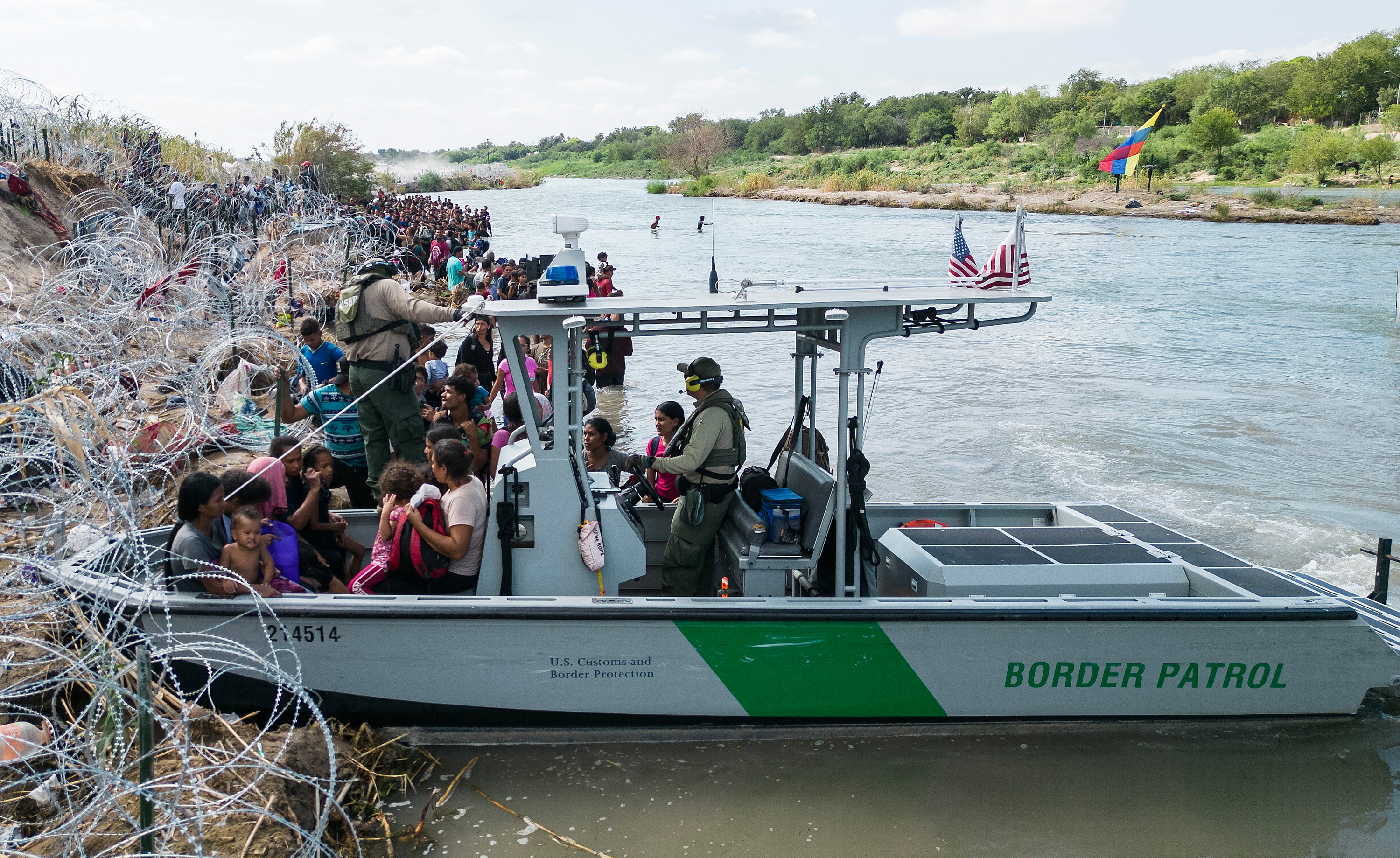 A US Border Patrol boat picks up families with young children as other migrants wait for an opening in the razor wire barrier to cross into the United States, in Eagle Pass, Texas, on September 25.