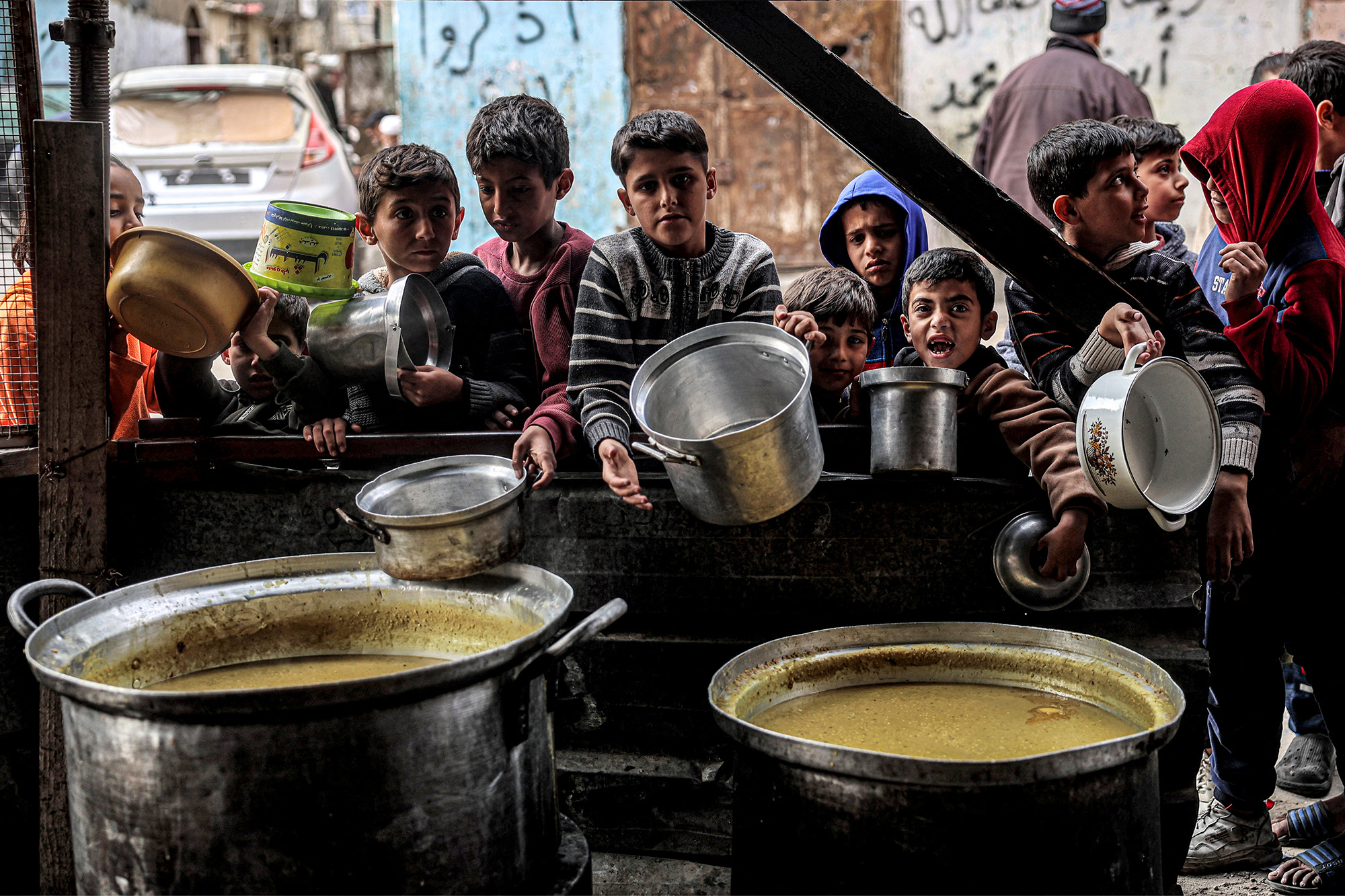Boys wait while holding empty pots with other displaced Palestinians queueing for meals provided by a charity organisation in Rafah, Gaza, on March 16.