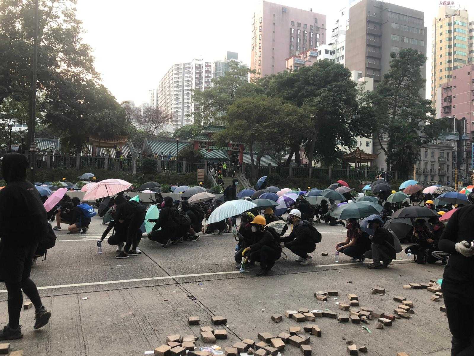 Protesters on Nathan Road, Kowloon, take cover under umbrellas and makeshift shields. Helen Regan/CNN