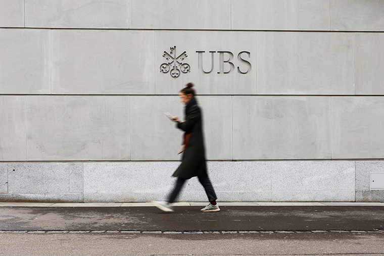 A person walks in front of a logo of the Swiss bank UBS in Zurich, Switzerland March 20.