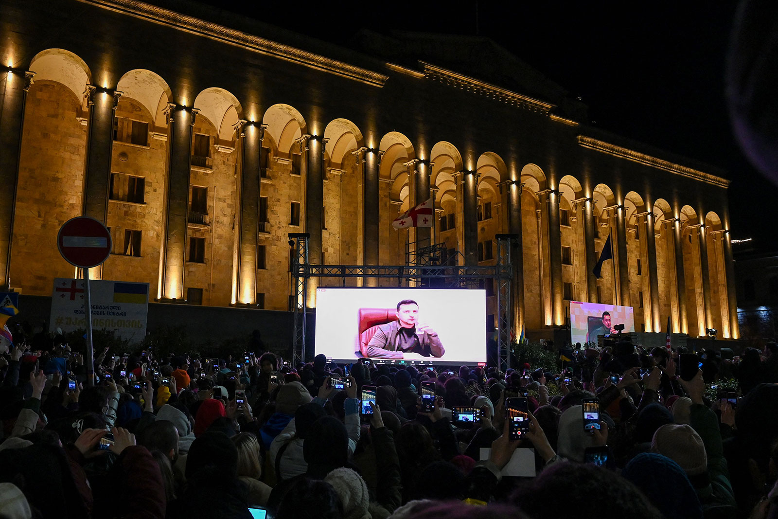 Протестующие в Тбилиси, Грузия, наблюдают за выступлением президента Украины Владимира Желенского 4 марта.