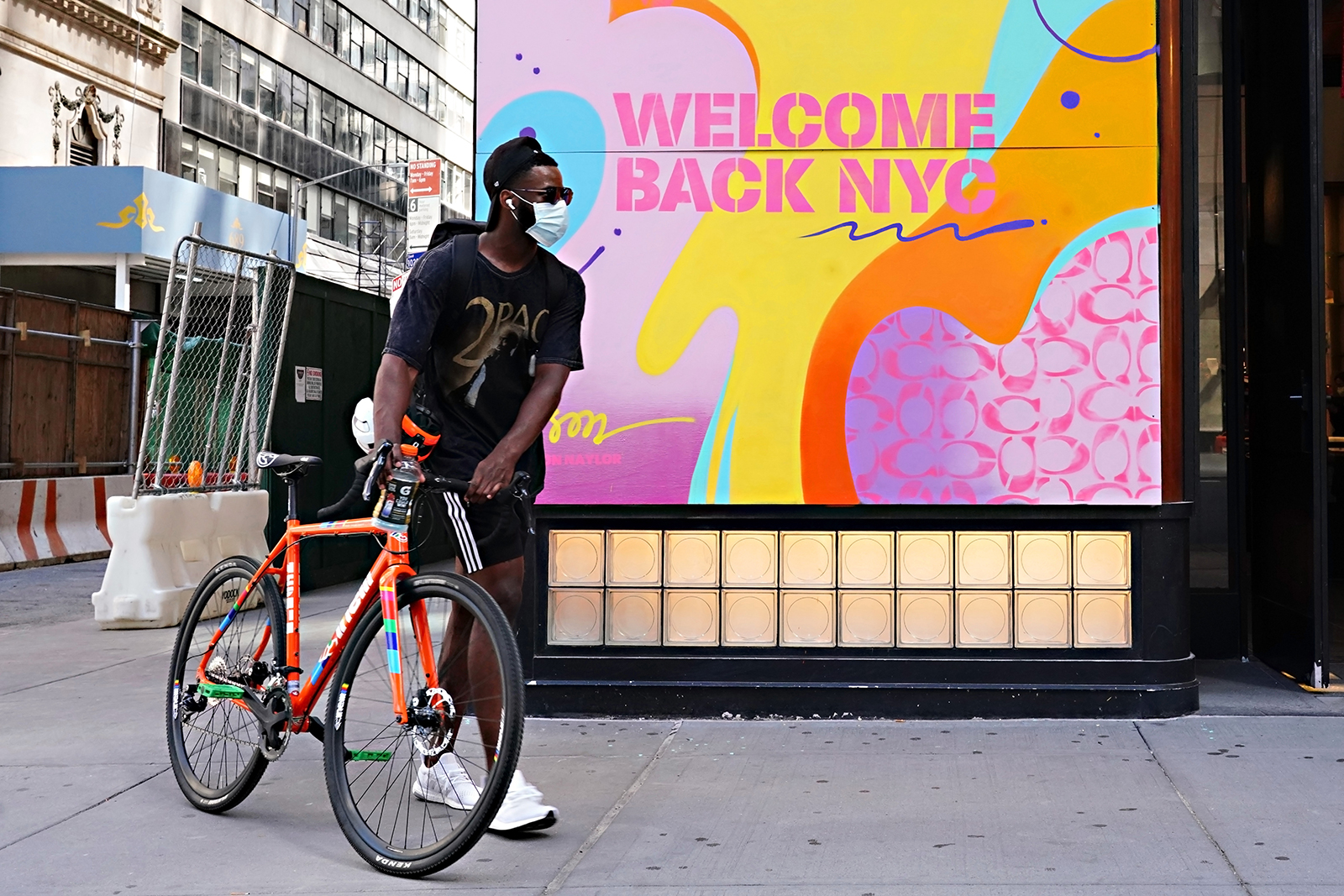 A man wearing a mask walks a bike in New York as the city continues Phase 4 of re-opening on Monday. 
