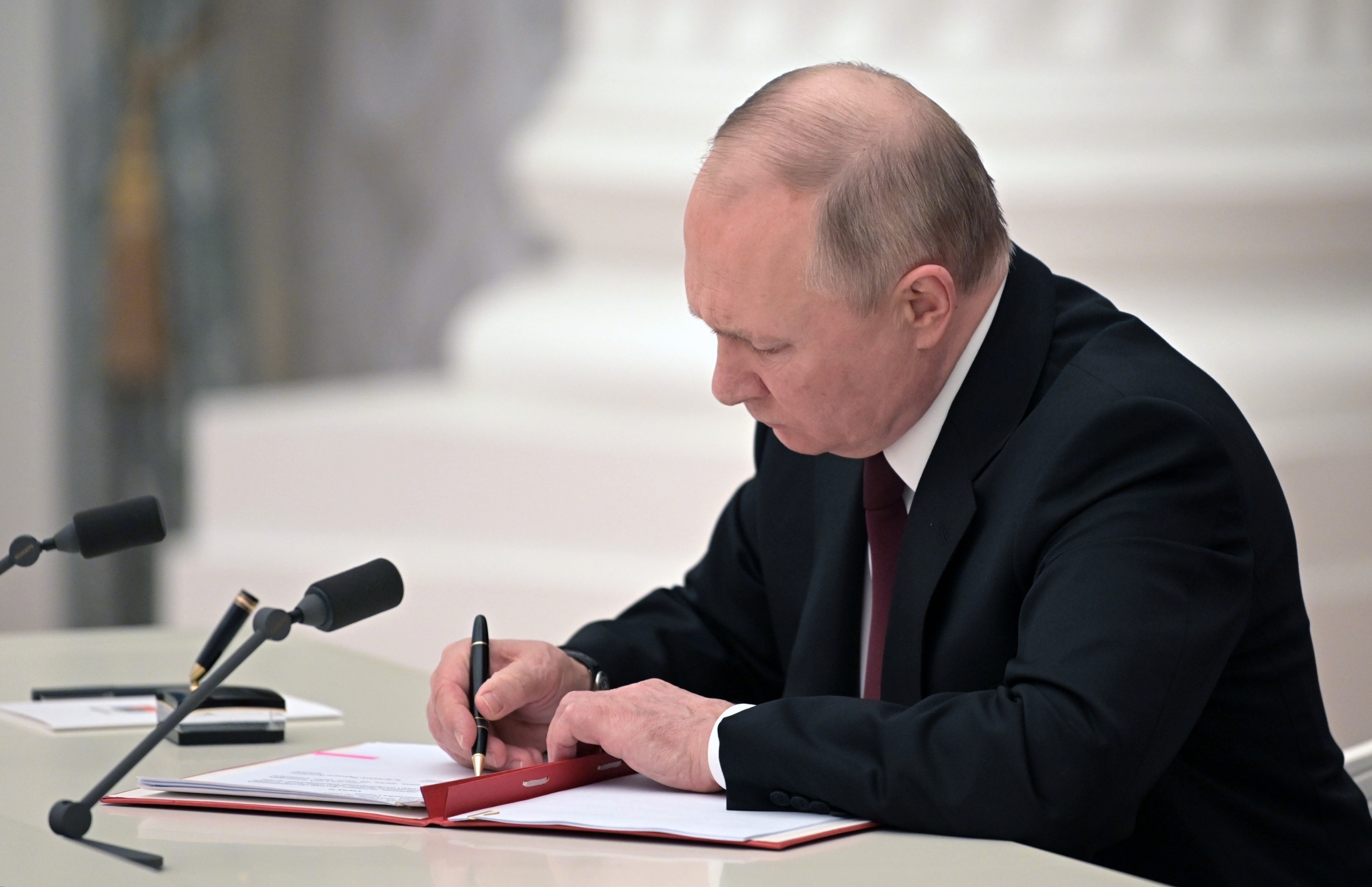 Russian President Vladimir Putin signs a document recognizing the independence of separatist regions in eastern Ukraine on February 21 in Moscow, Russia. 