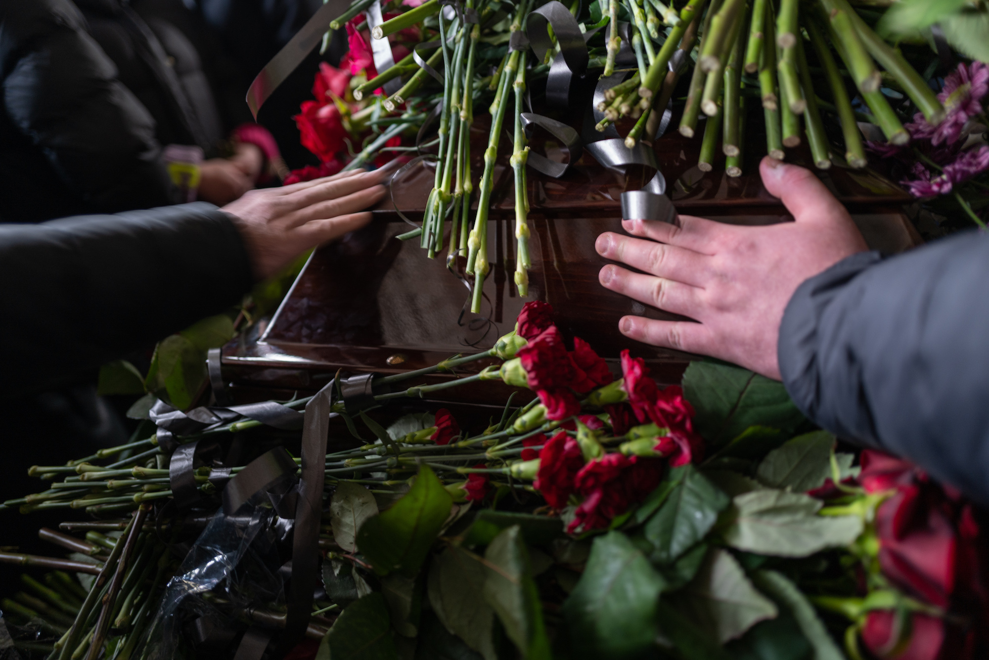 People lay flowers at the coffin of Mykhailo Korenovsky, a boxing coach and father killed in a Russian missile strike on an apartment building on Tuesday in Dnipro.