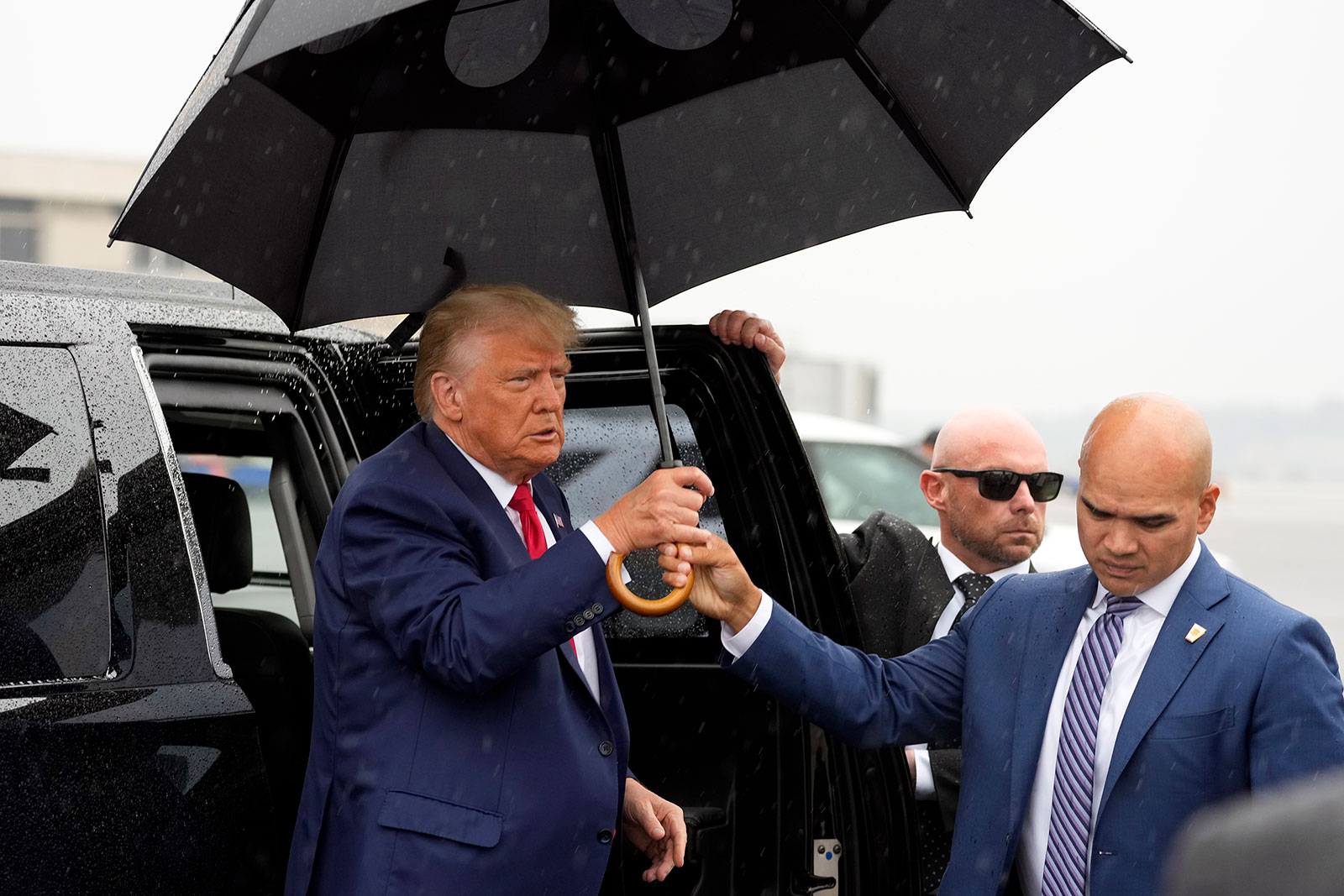 Valet Walt Nauta hands former President Donald Trump an umbrella at Ronald Reagan Washington National Airport, on Thursday, August 3.