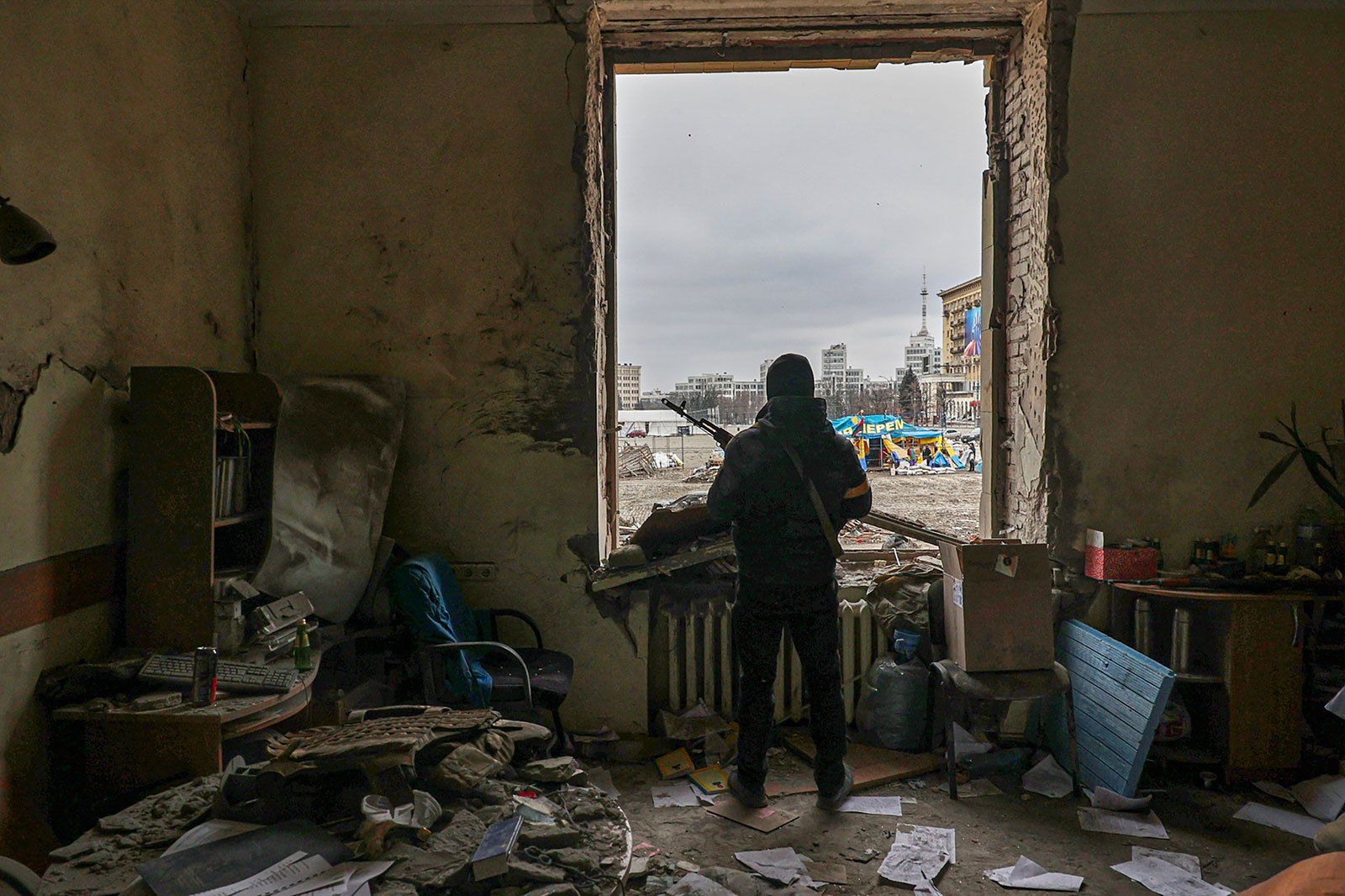 Një pjesëtar i Forcave të Mbrojtjes Territoriale të Ukrainës qëndron brenda ndërtesës së dëmtuar të administratës.
