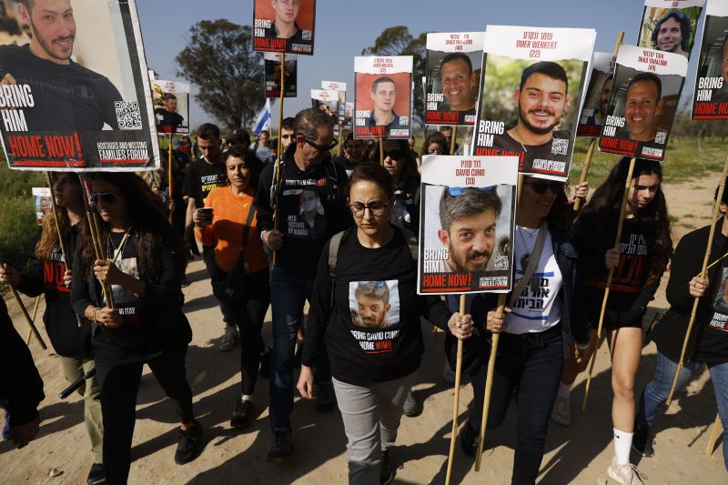 Families and supporters of Israeli hostages held in Gaza hold signs depicting some of the hostages in Re'im, Israel, as they begin a four-day protest march to Jerusalem on February 28. 