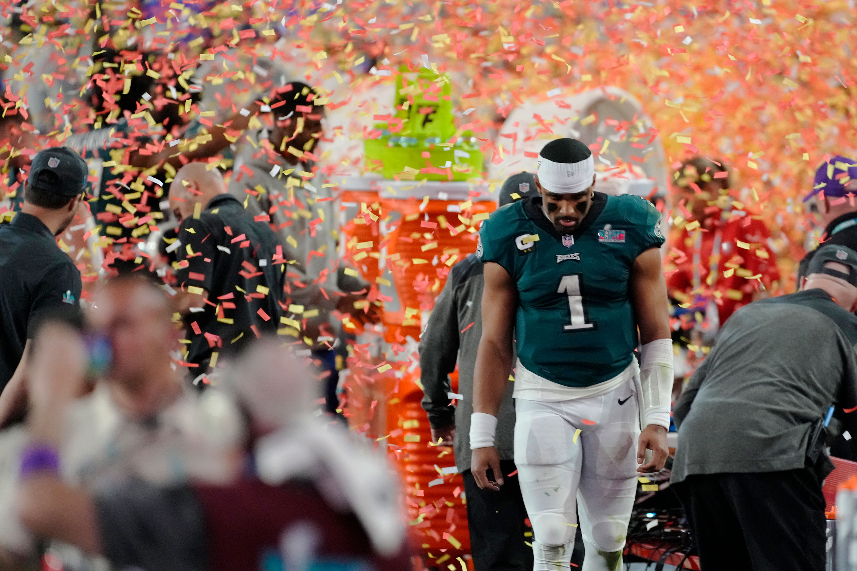 Philadelphia Eagles quarterback Jalen Hurts walks off the field as confetti rains down.