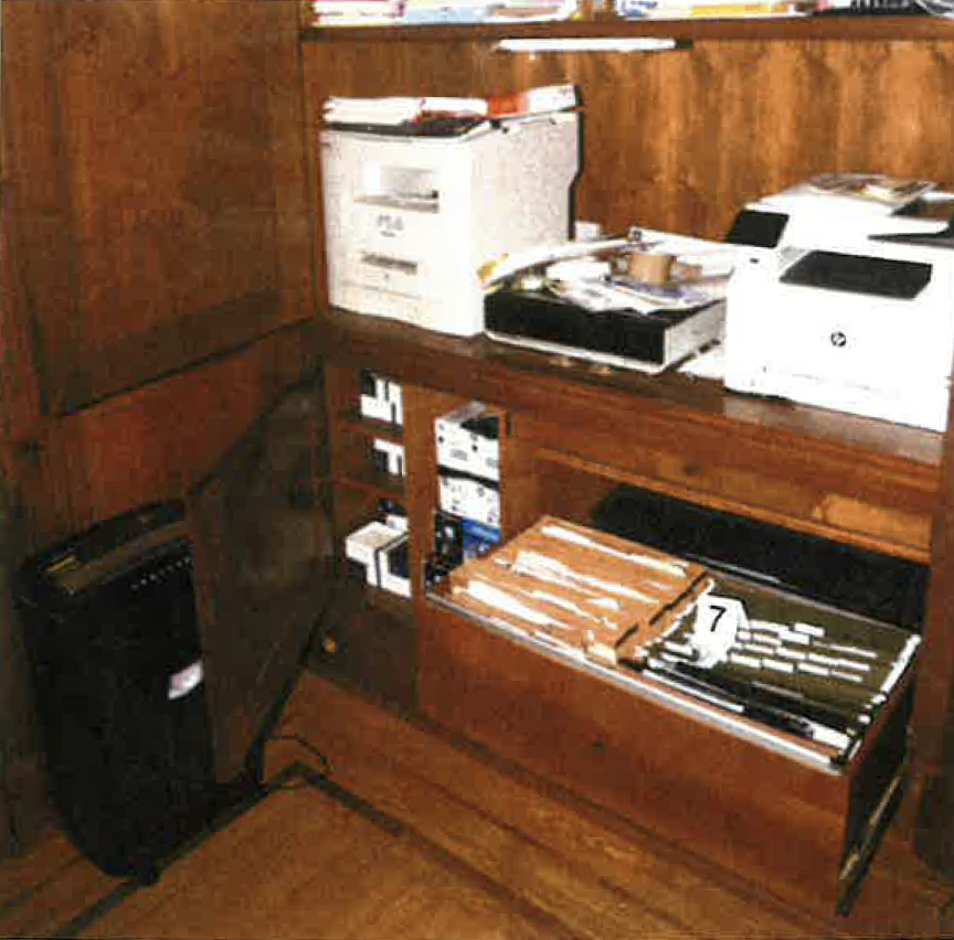 This photo from page 93 of the report shows the cabinet under printers in Delaware home’s main-floor office, containing three seized notebooks.