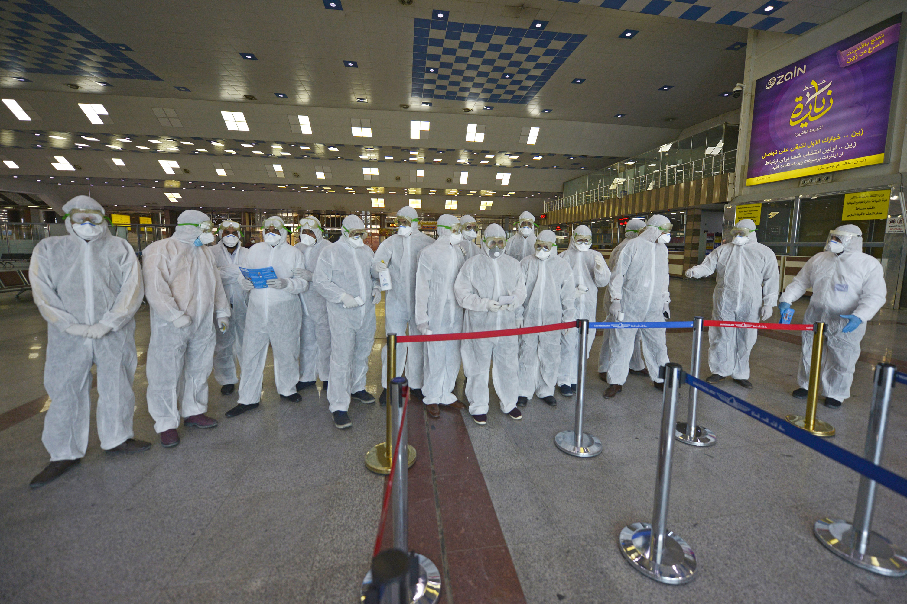 Medical staff in protective gear wait for Iraqi passengers returning from Iran at Najaf International Airport on March 5, 2020. 