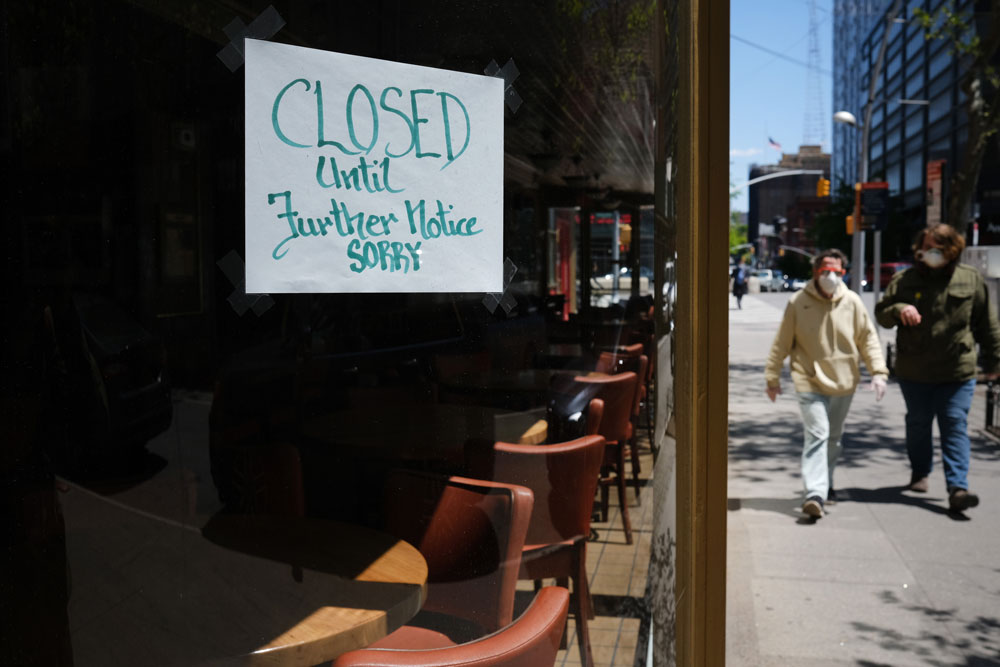 People walk through a shuttered business district in Brooklyn on May 12 in New York City.