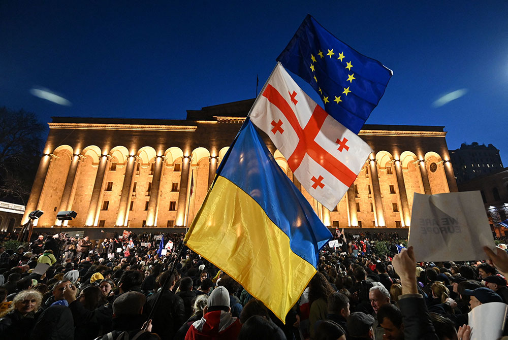 Protesters wave the Georgian, Ukrainian and European flags during a demonstration outside Georgia's Parliament in Tbilisi on March 8.
