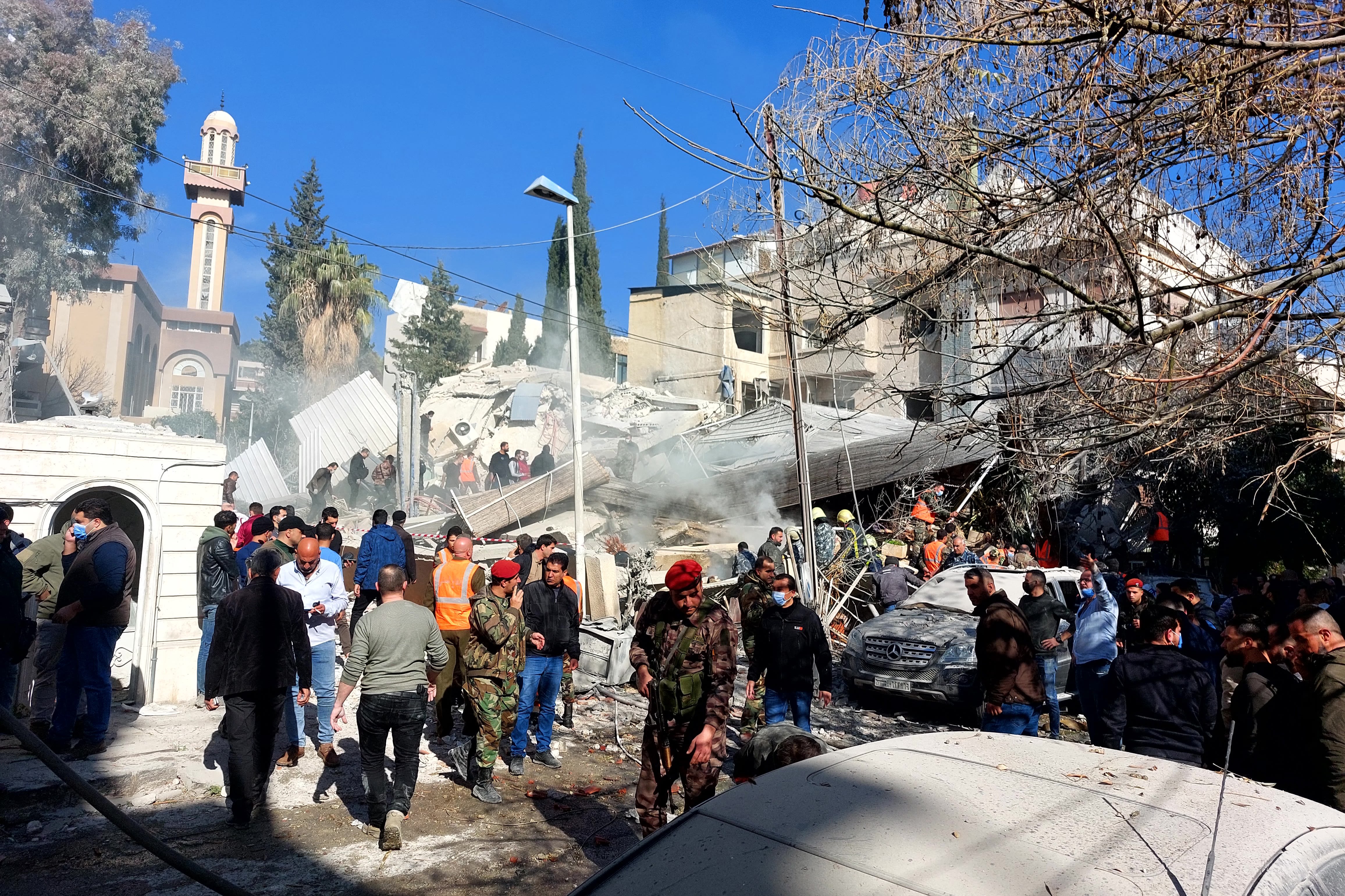 אנשים מתאספים מול בניין שנהרס בתקיפה ישראלית שדווחה בדמשק, סוריה, ב-20 בינואר.