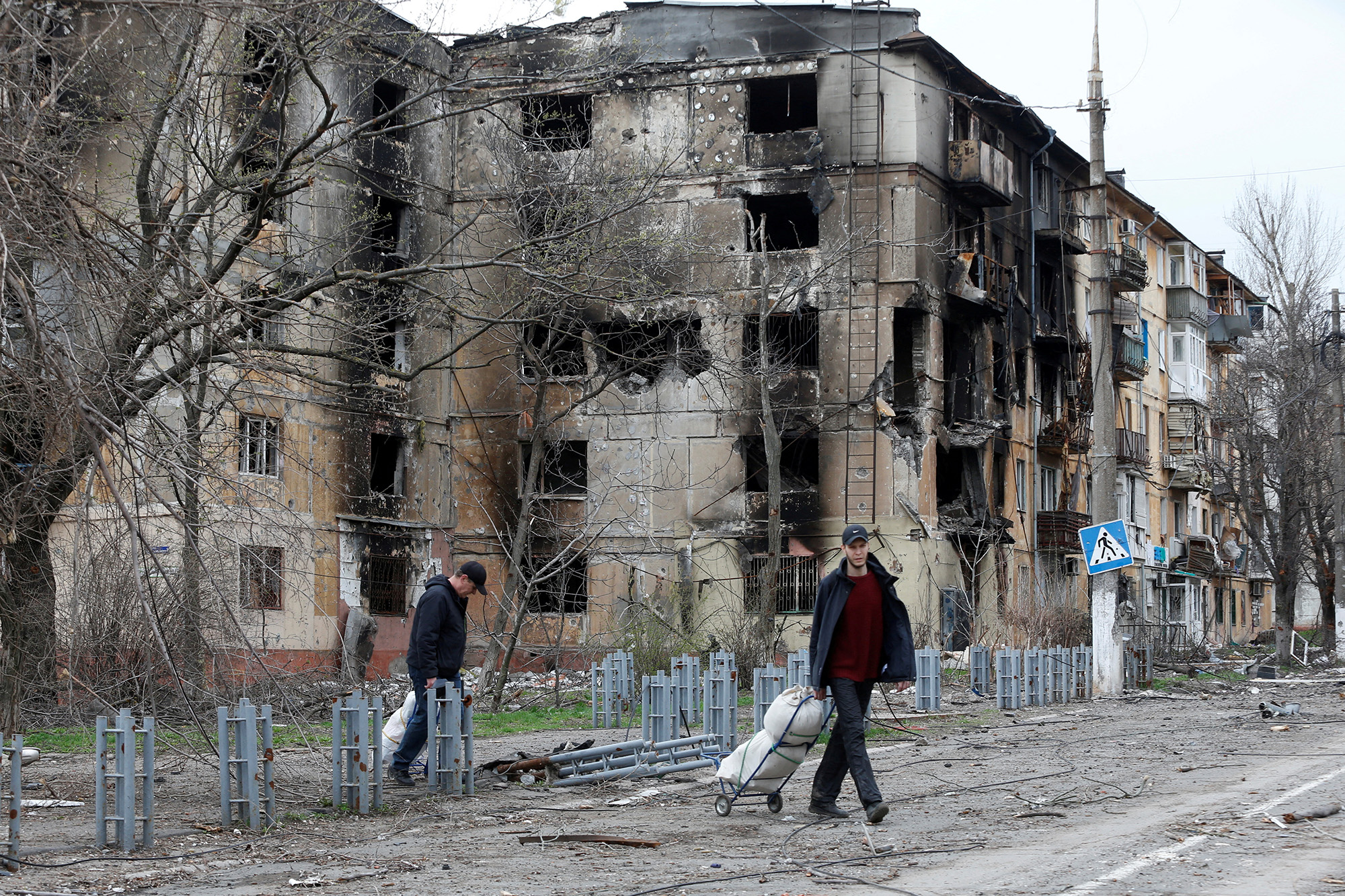 People walk past a heavily damaged residential building in the southern port city of Mariupol, Ukraine, on April 18.