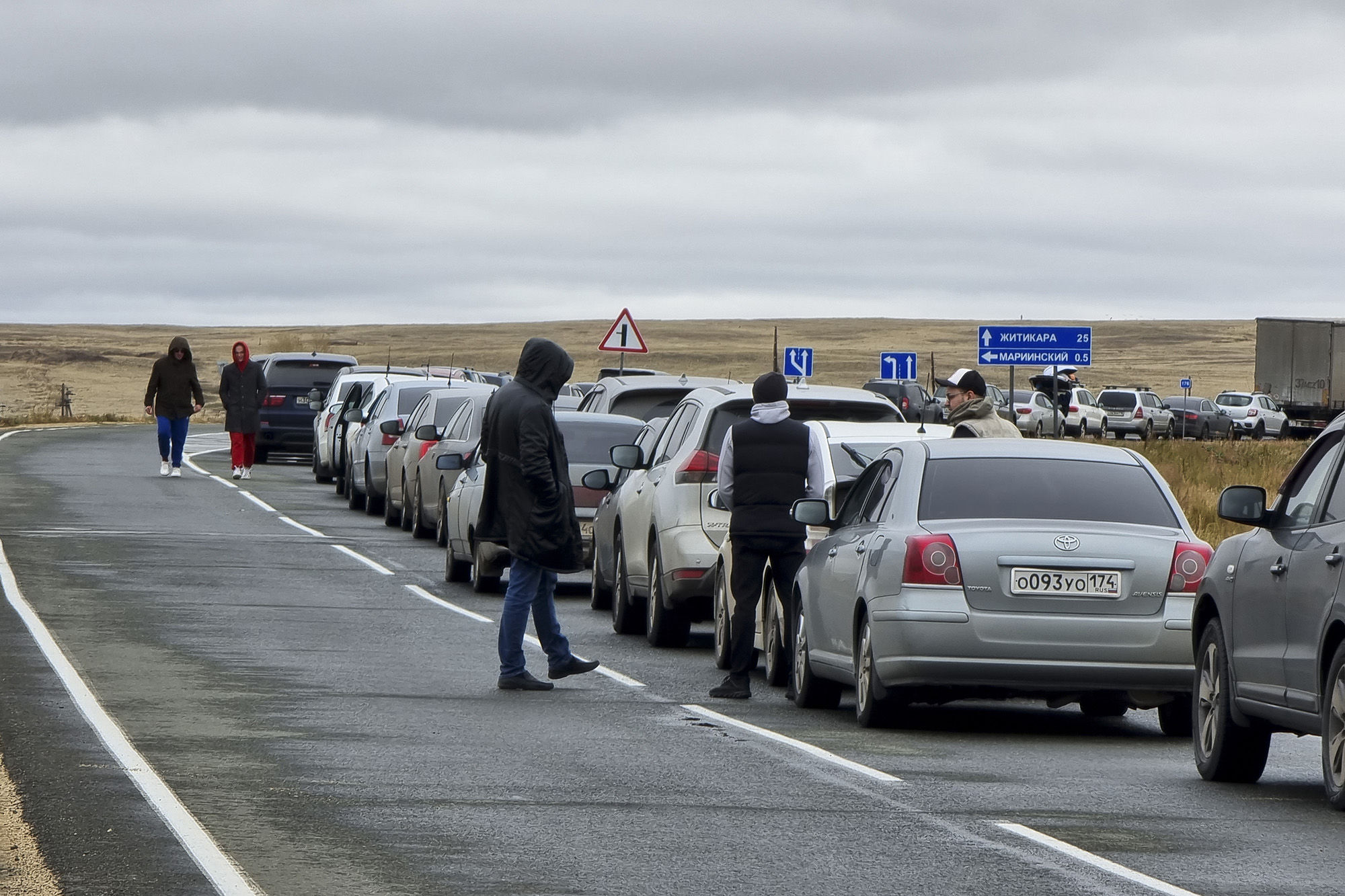 People walk next to their cars while queuing to cross the border into Kazakhstan at the Mariinsky border crossing, Russia, on September 27