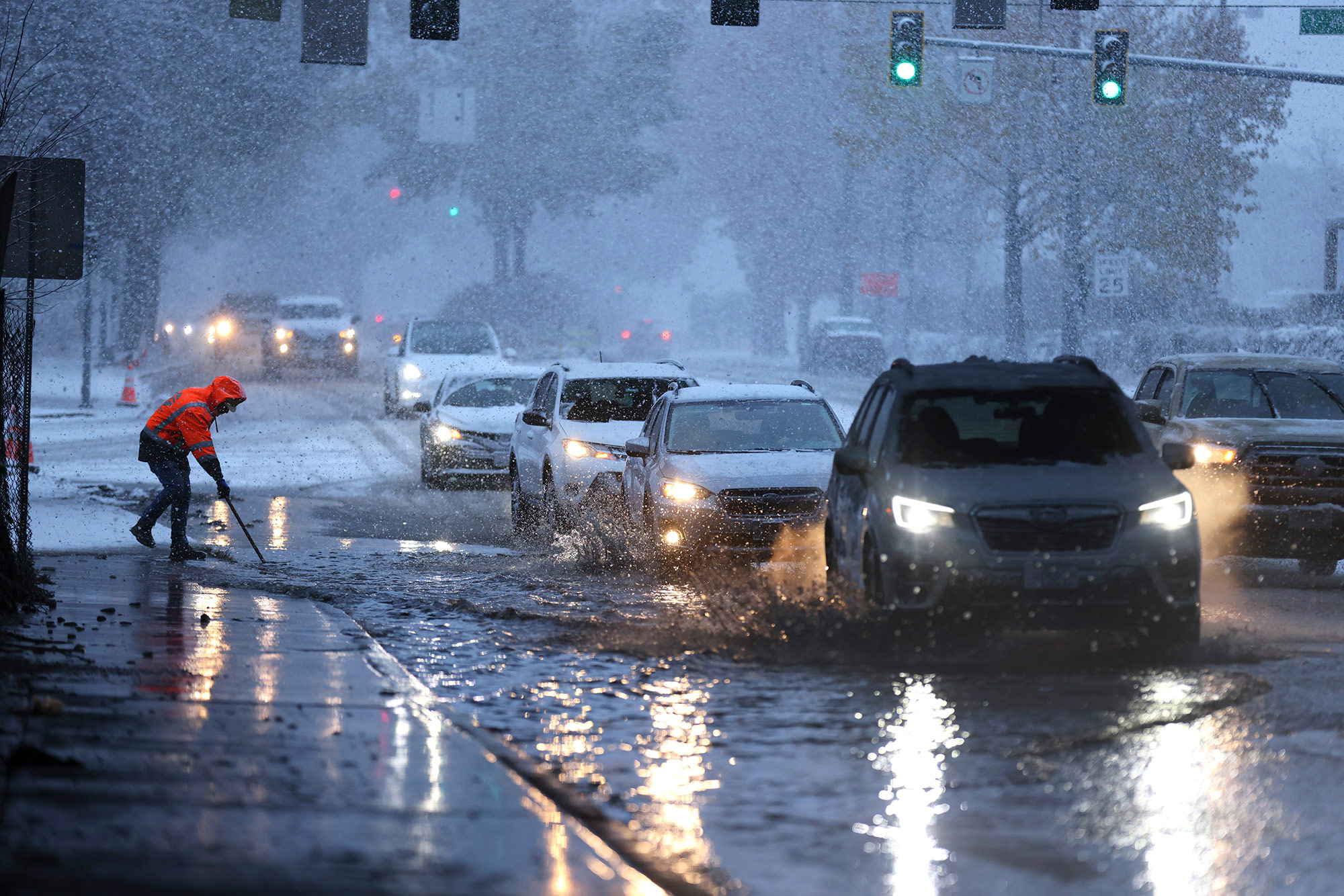 A worker from the Washington Department of Transportation clears a drain as drivers commute through snow on December 20, in Seattle, Washington. 