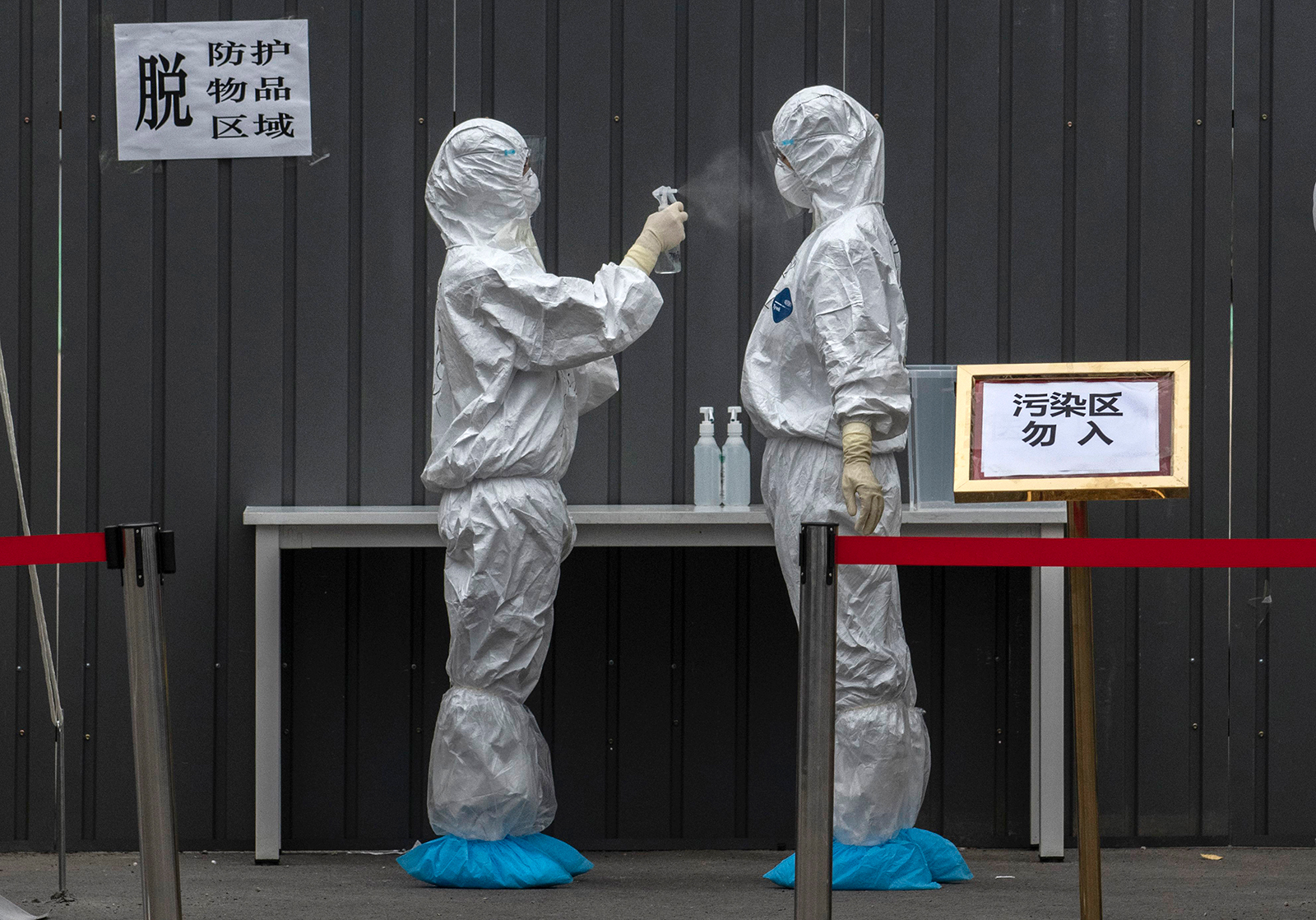 Chinese epidemic control workers wear protective suits as they disinfect each other after performing nucleic acid swab tests for Covid-19 on citizens at a government testing site in Xicheng District on June 24 in Beijing. 