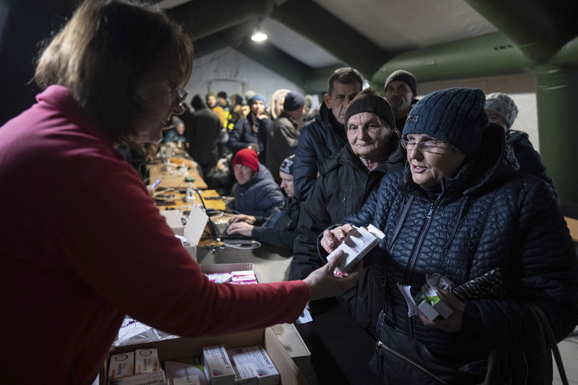 A woman receives medicine boxes from a volunteer at a heating tent, a “Point of Invincibility,” a government-built help station, in Kherson, Ukraine, on December 3.